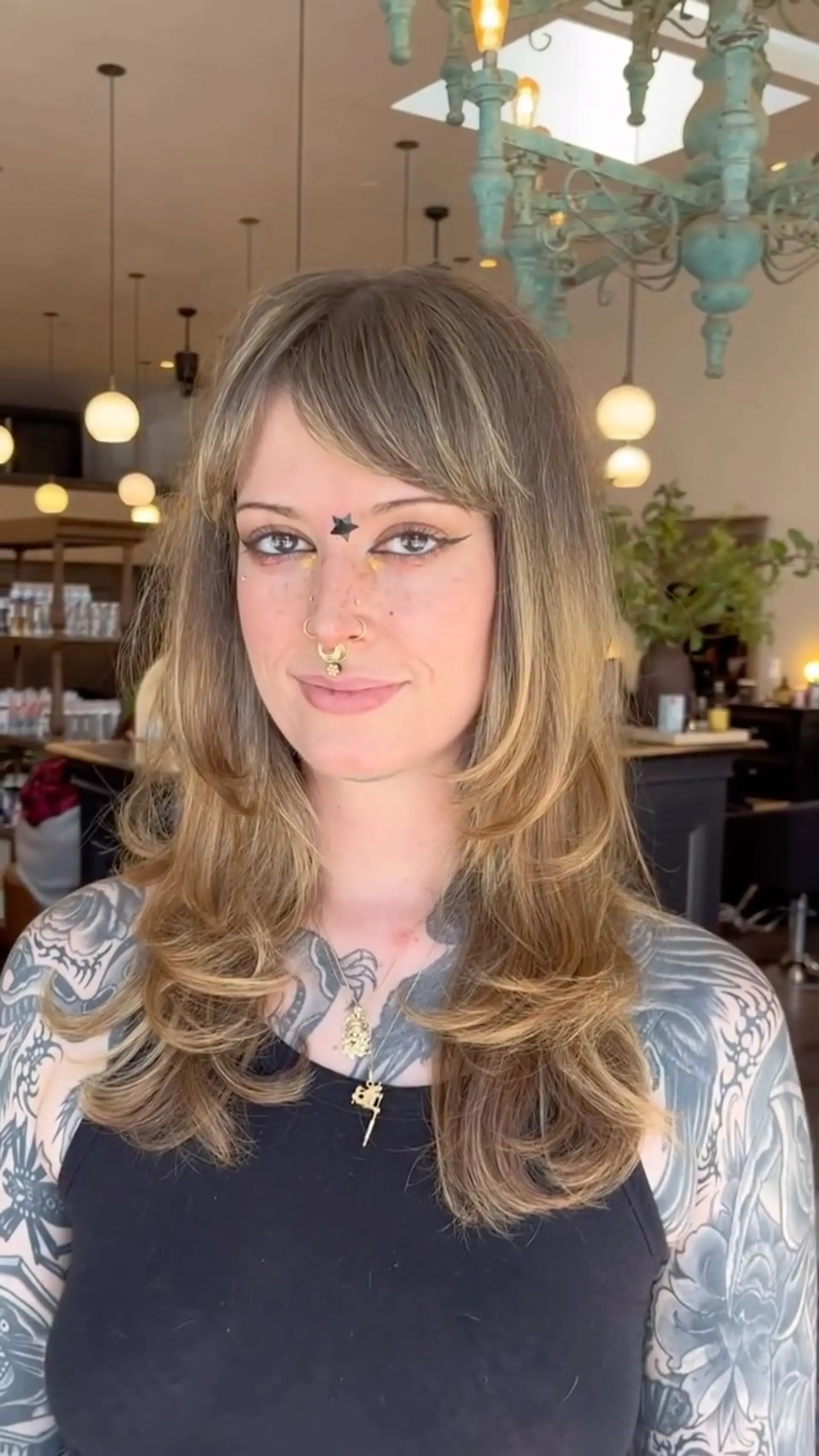Long cascading layered haircut featuring soft face-framing layers and wispy bangs with flipped ends. 1