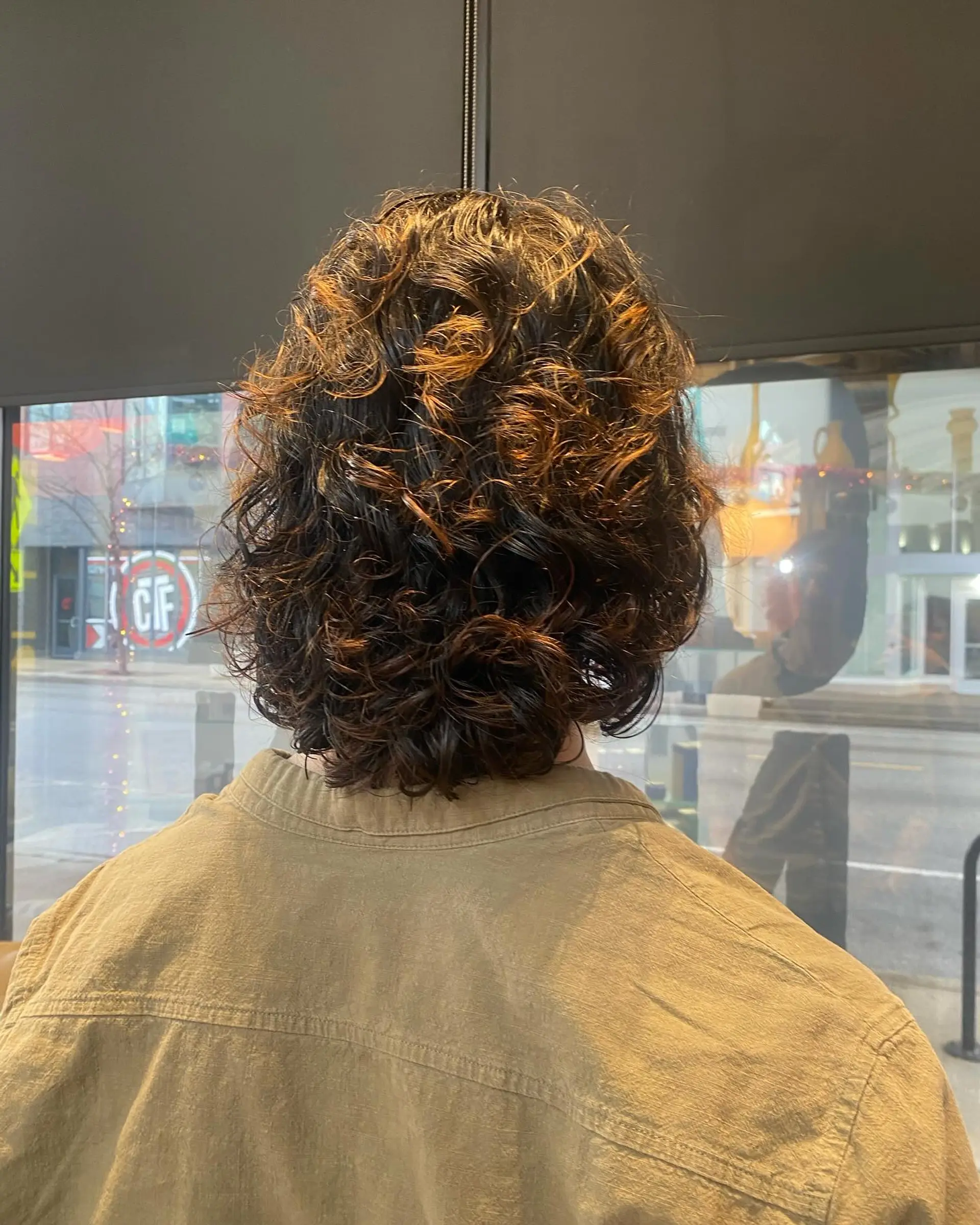 This is a medium-length curly shag with textured layers. The bronde color comes from a balayage. 1