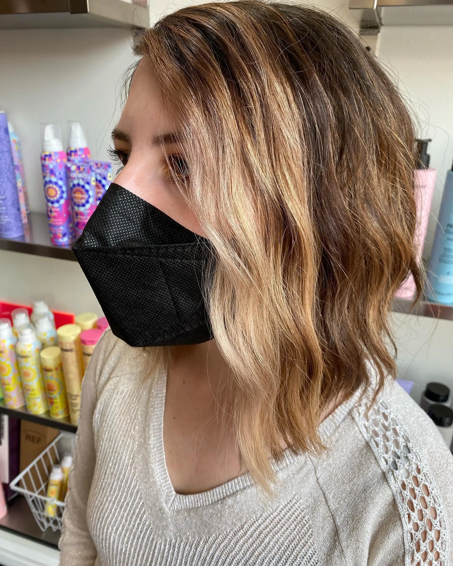 A dimensional textured lob with soft waves featuring bright golden-blonde balayage highlights seamlessly blended into a natural brown base. 1