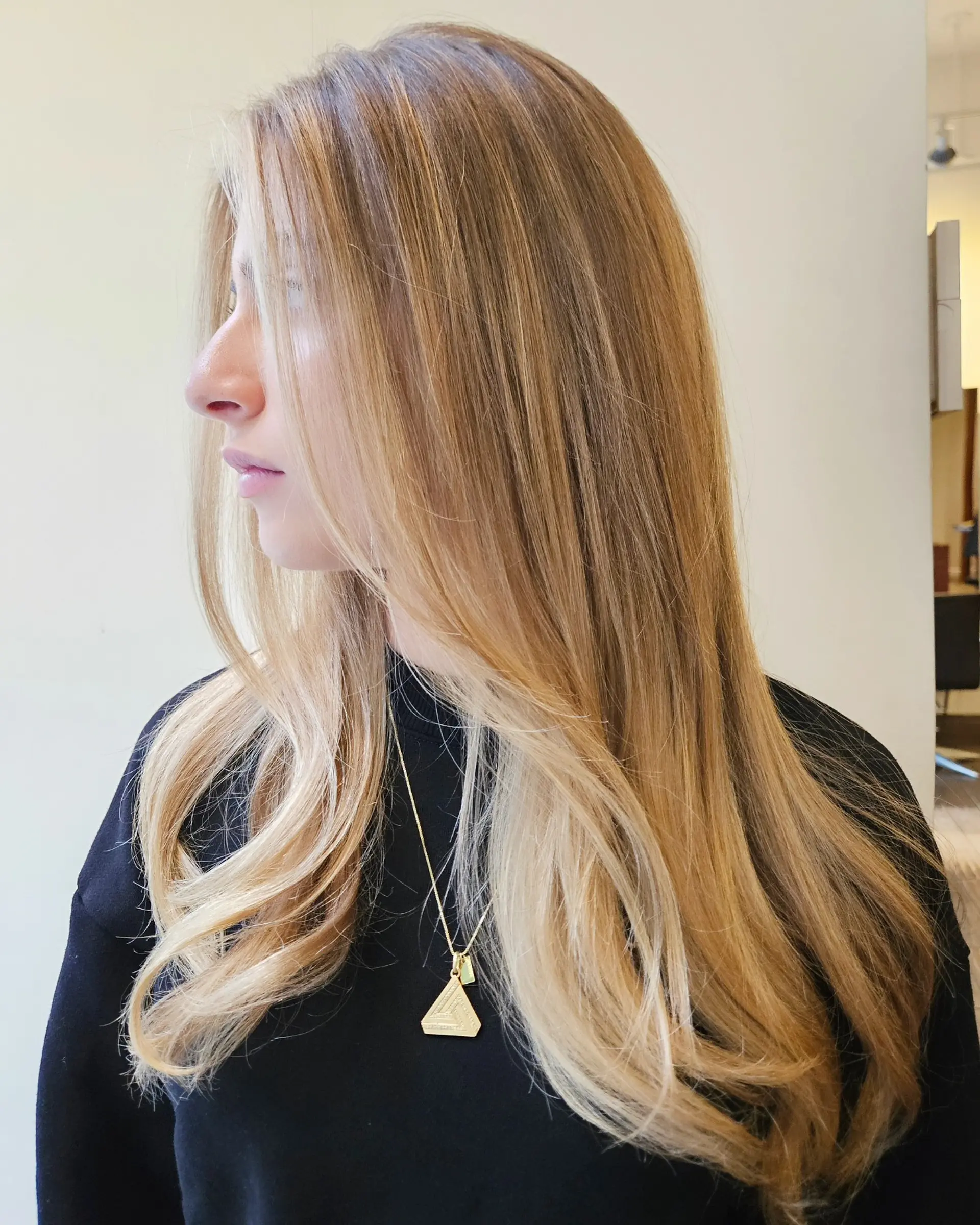 Long warm blonde hair featuring dimensional highlights and face-framing layers styled with a smooth blowout. 1