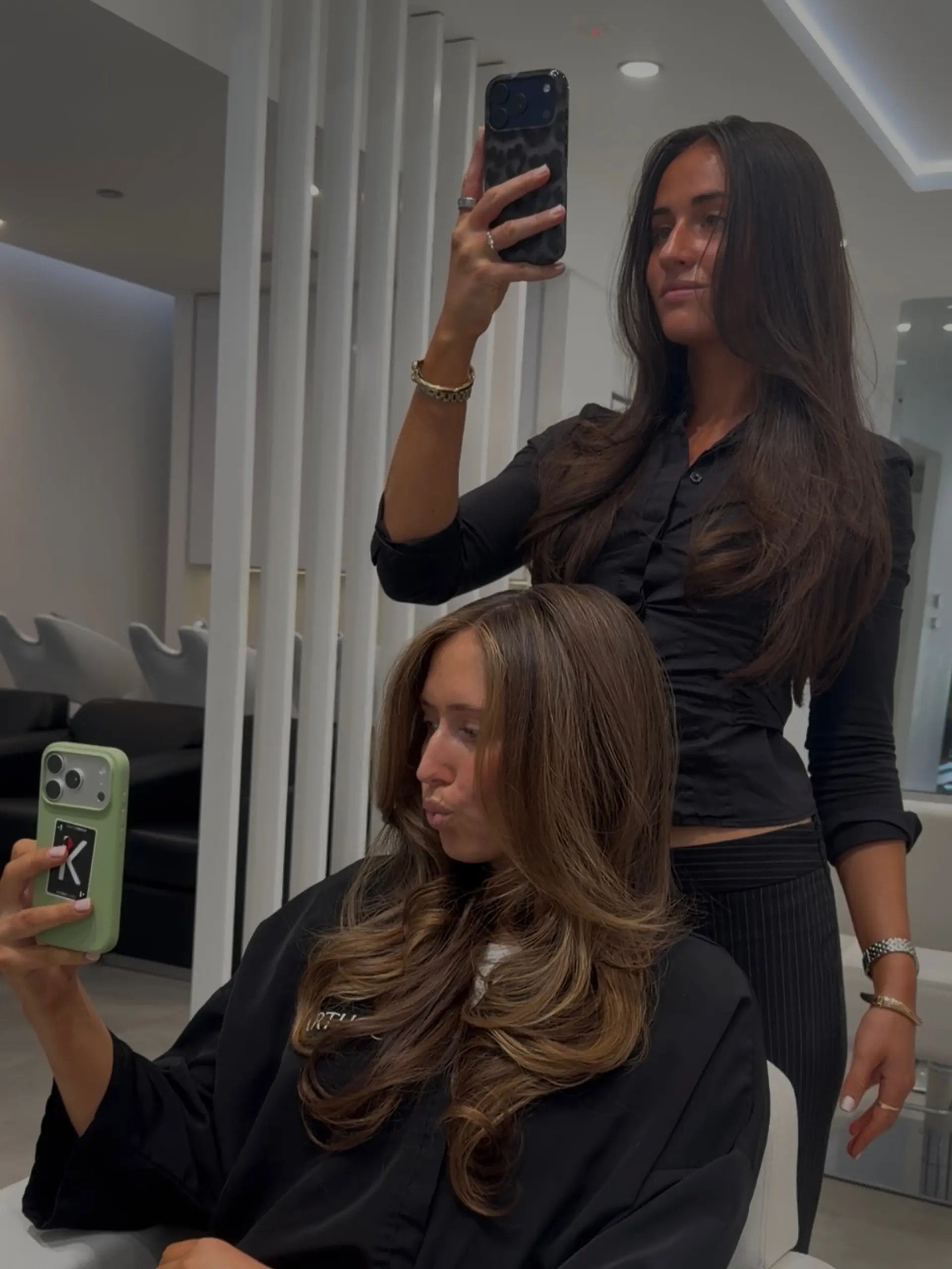 Long brown hair styled in a voluminous blowout with soft outward-turned layers and face-framing curtain pieces. 1