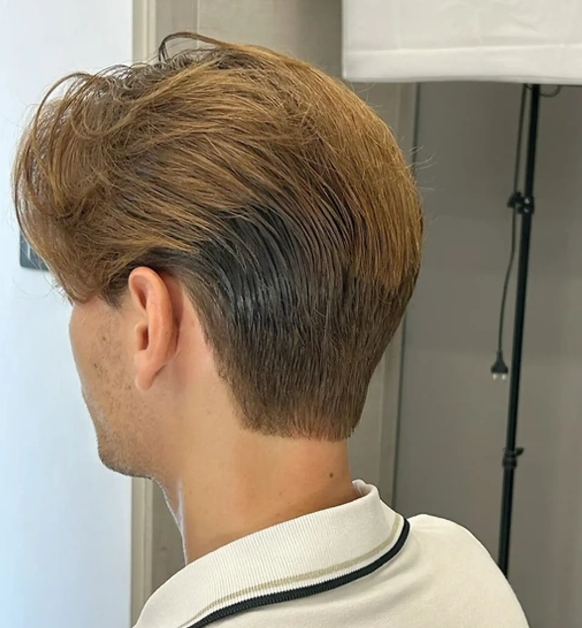 Slicked-back with a tapered undercut, featuring brown top layers and black shaded nape, creating a textured and voluminous look. 1