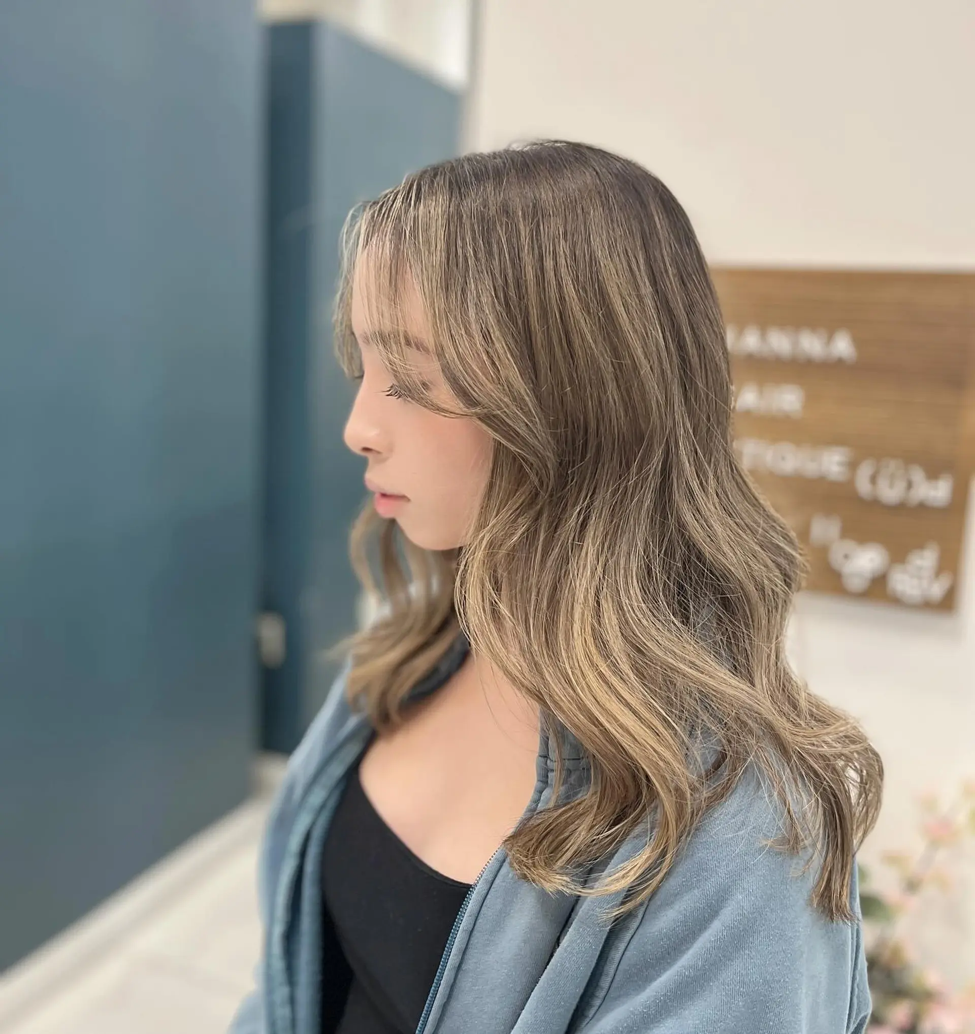 Dimensional ash blonde balayage styled into loose, elegant waves with soft curtain bangs. 1