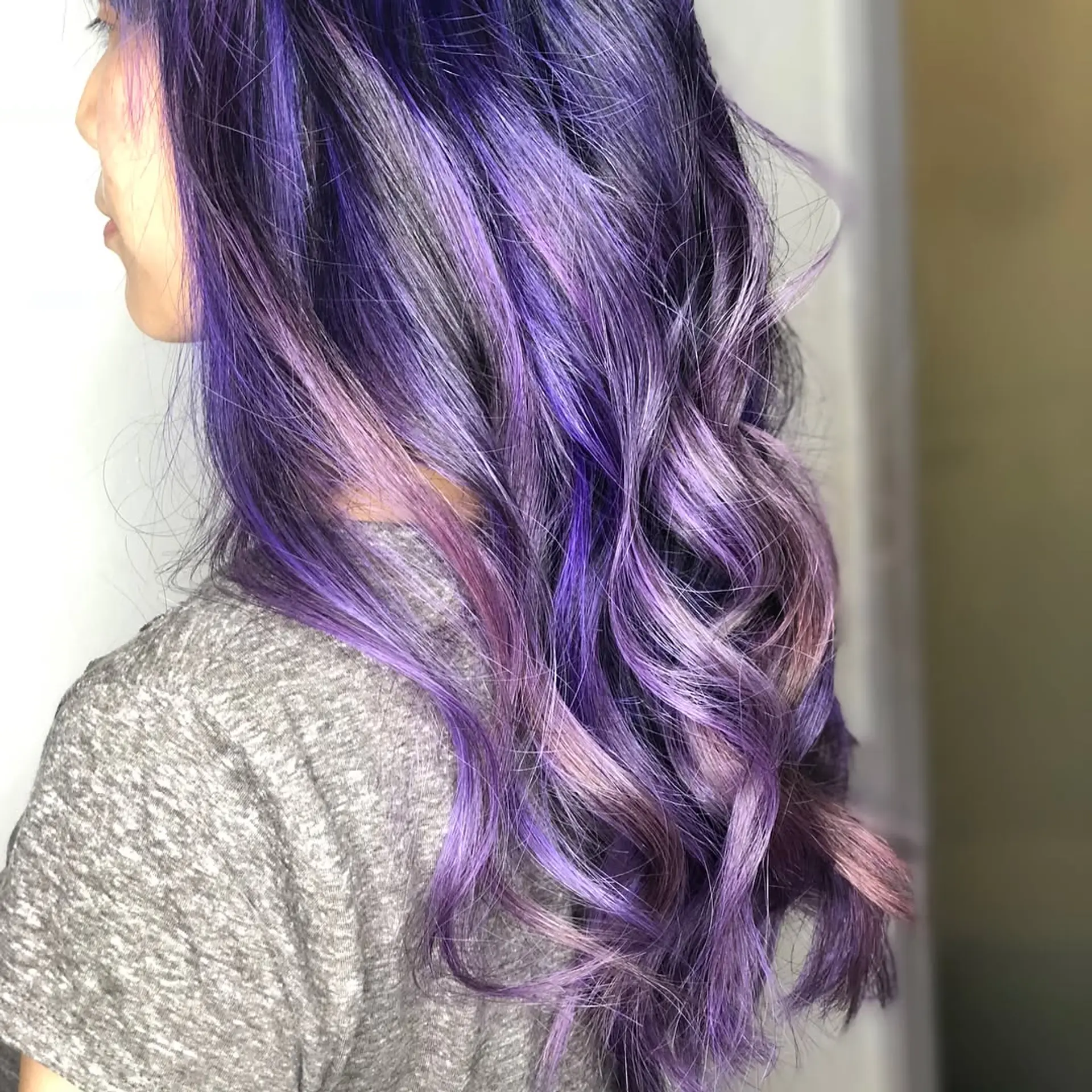 Long layered hair styled in soft, loose waves, colored in a blend of rich violet, purple, and pastel lavender tones. 1
