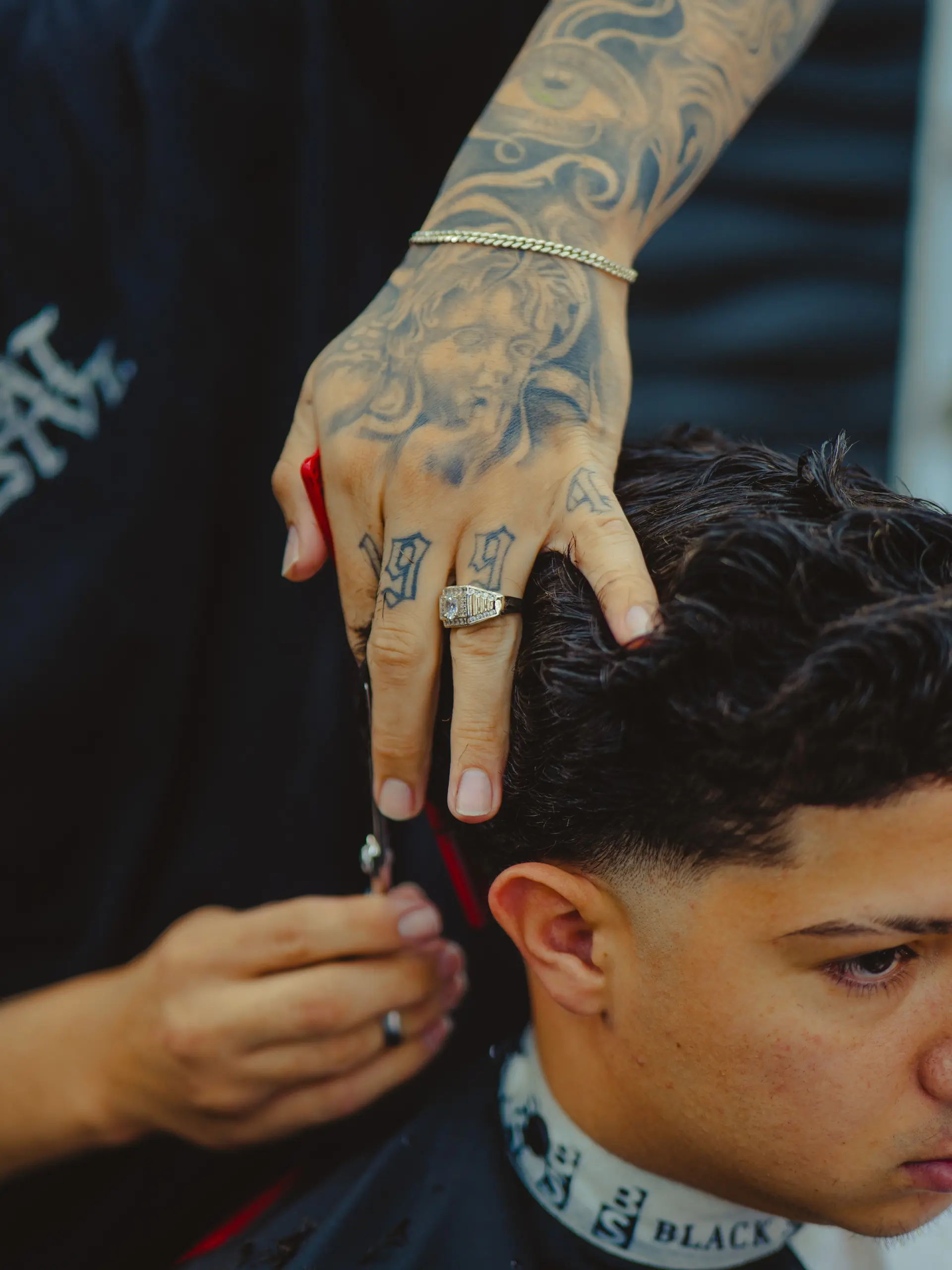 A clean low taper fade around the temple and ear with a scissor-cut textured wavy top. 1