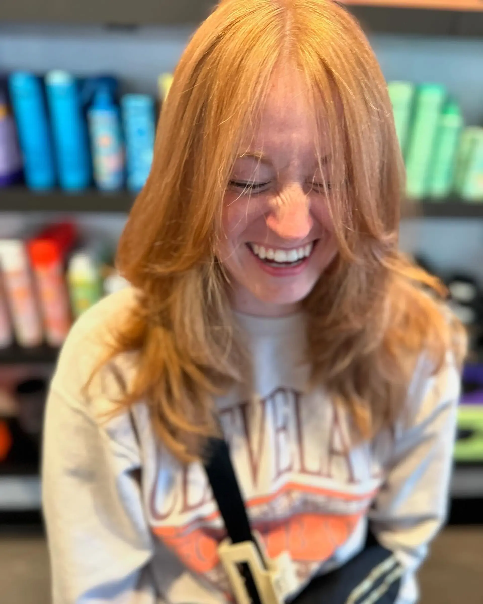 Medium-length strawberry blonde hair cut into a textured butterfly style with soft face-framing layers and wispy curtain bangs. 1