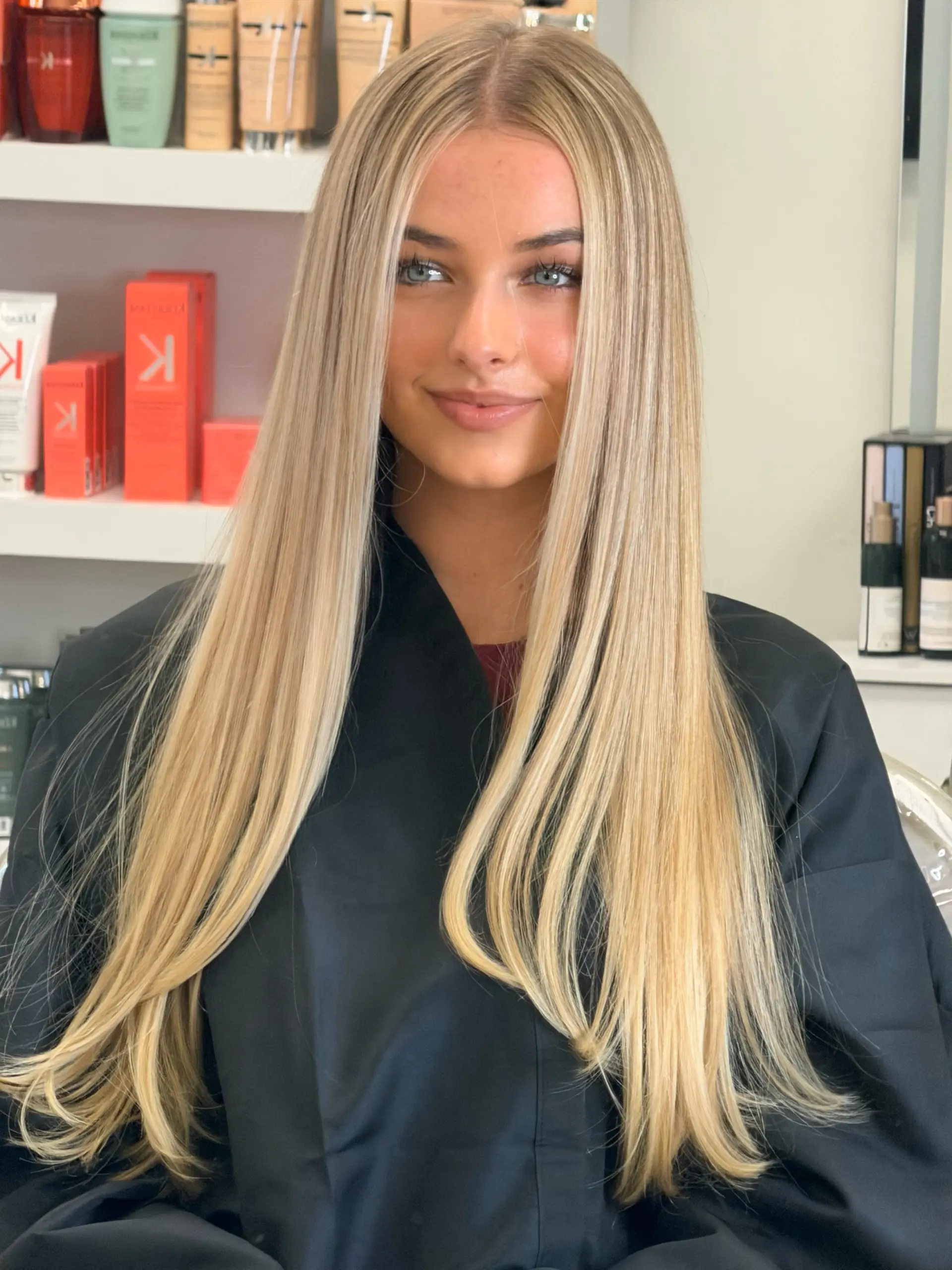 Extra-long, smooth blonde hair styled straight with a center part and soft dimension. 1