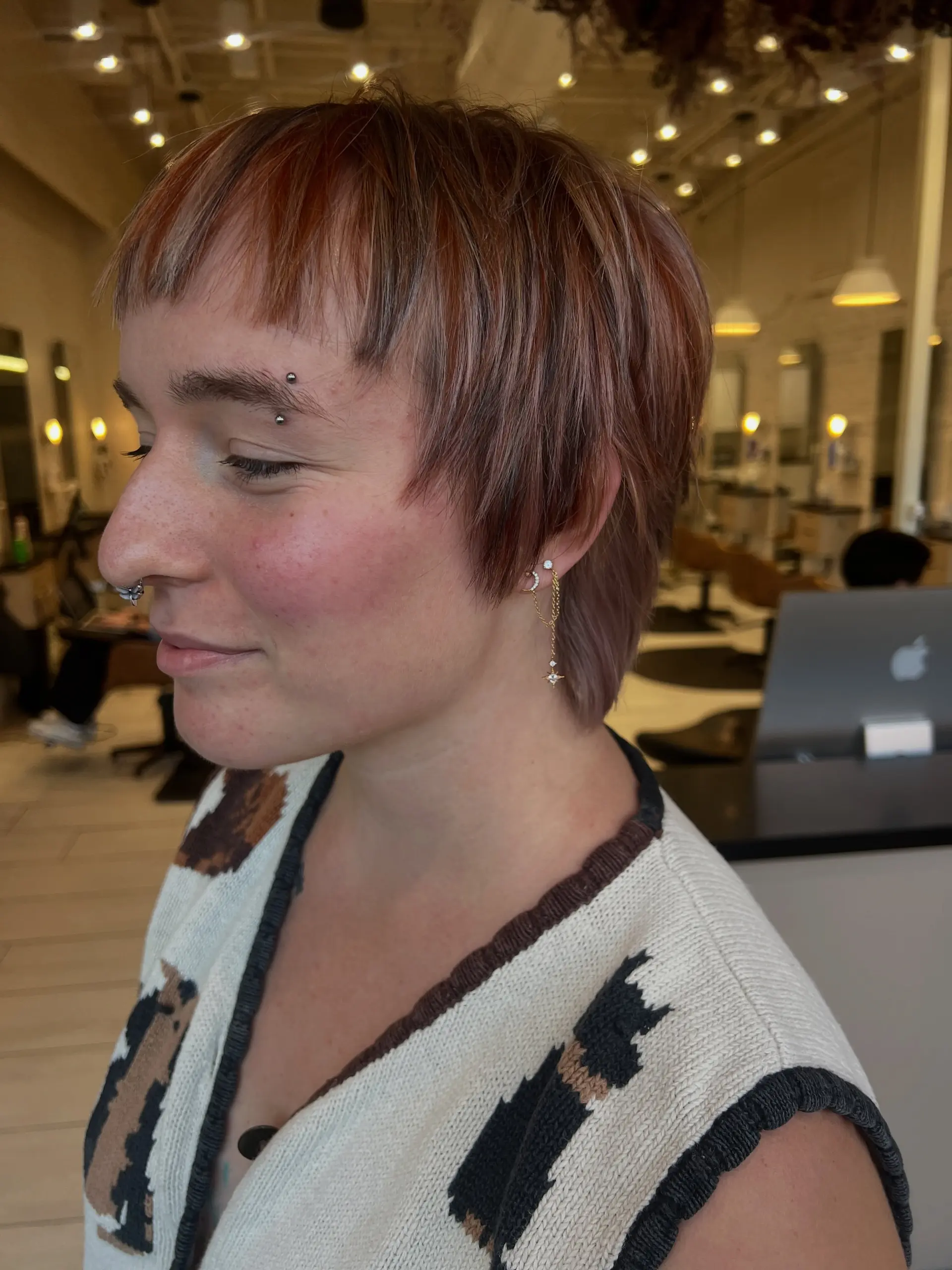 A textured short pixie cut featuring choppy micro bangs, tapered sides, and a multi-tonal calico color blend. 1