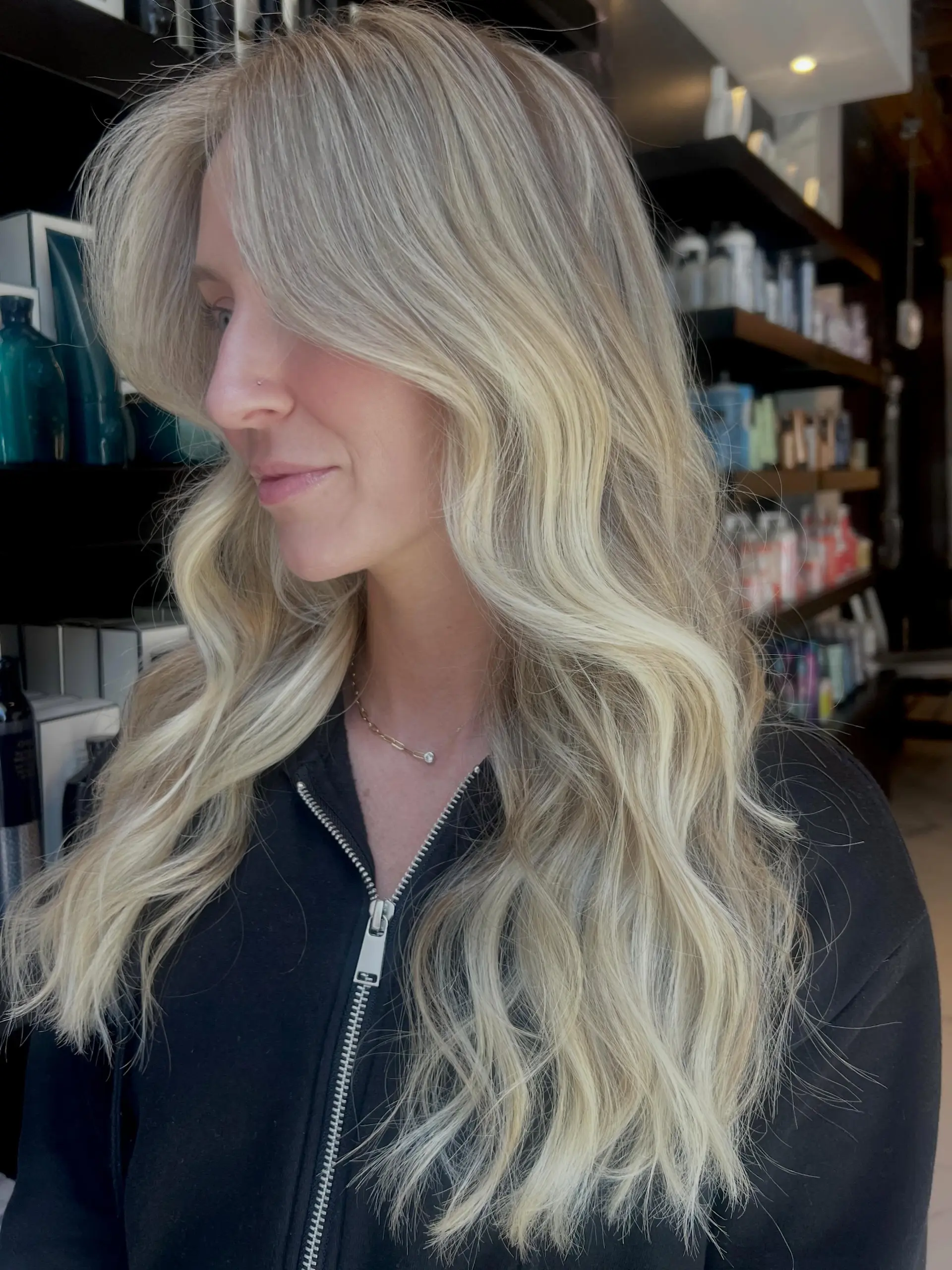 Long dimensional baby blonde hair cut with face-framing layers and styled in soft, cascading waves. 1