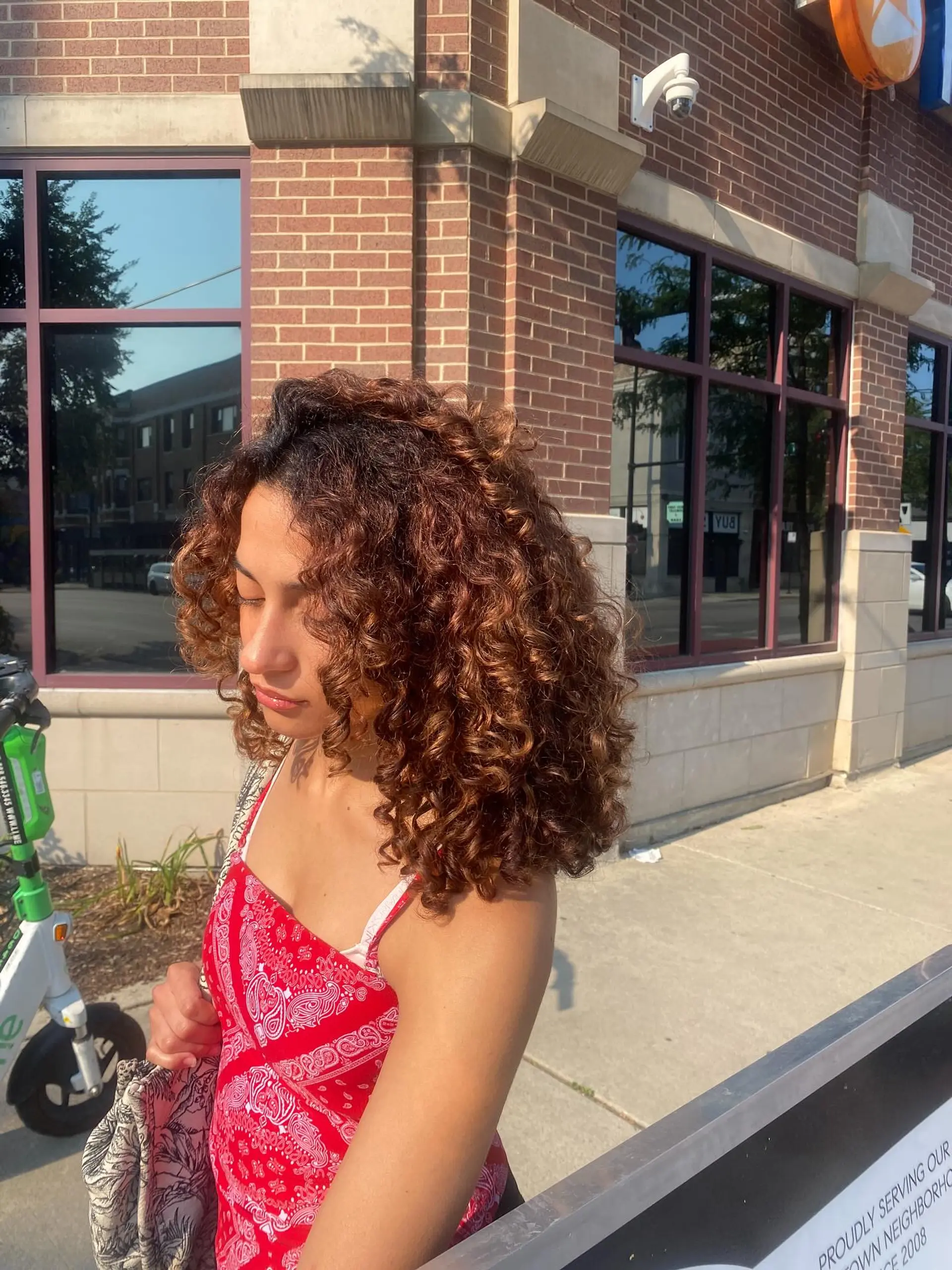 A stylish, medium-length bob with bouncy, defined curls and a rich copper color. 1