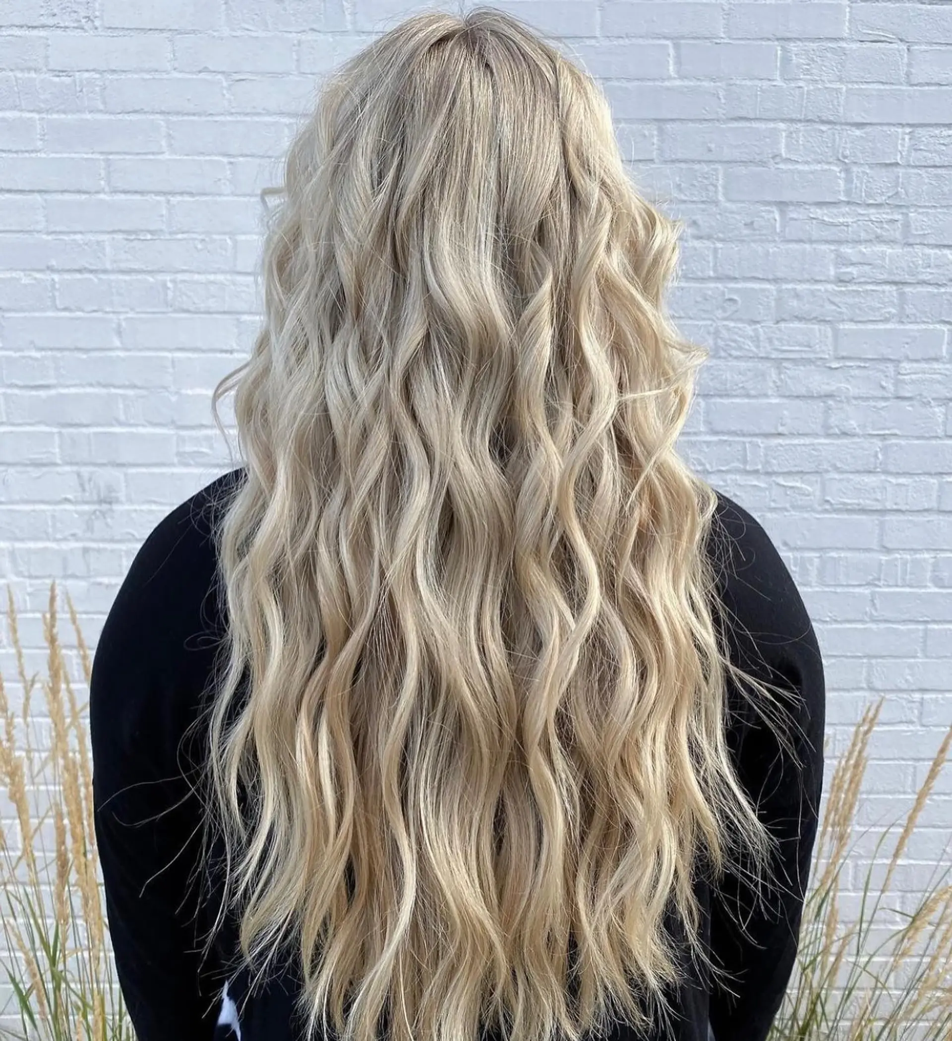 Extra-long bright blonde hair styled with loose, dimensional textured beach waves cascading down the back. 1