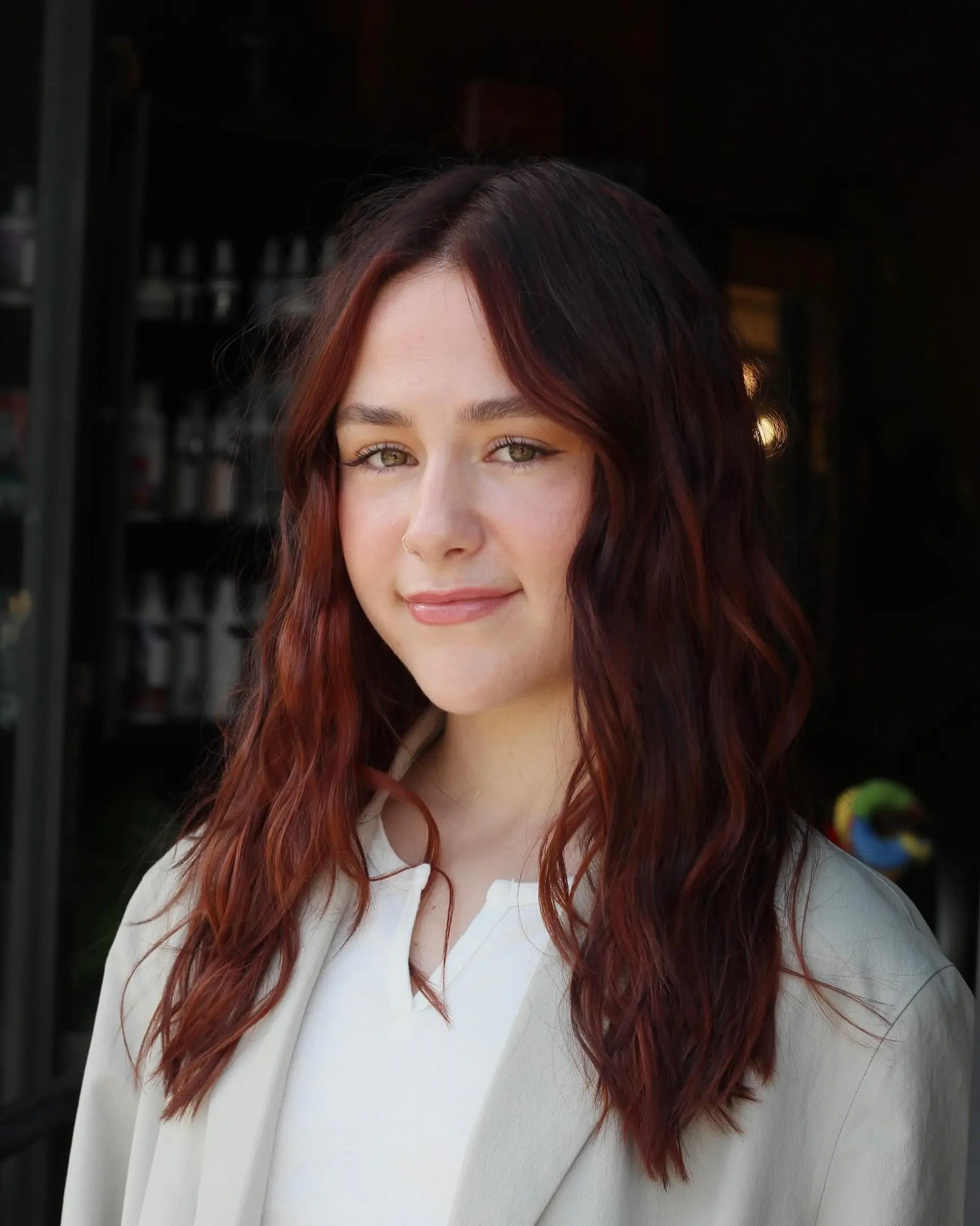 Long soft copper balayage styled with textured, lived-in waves and a center part. 1