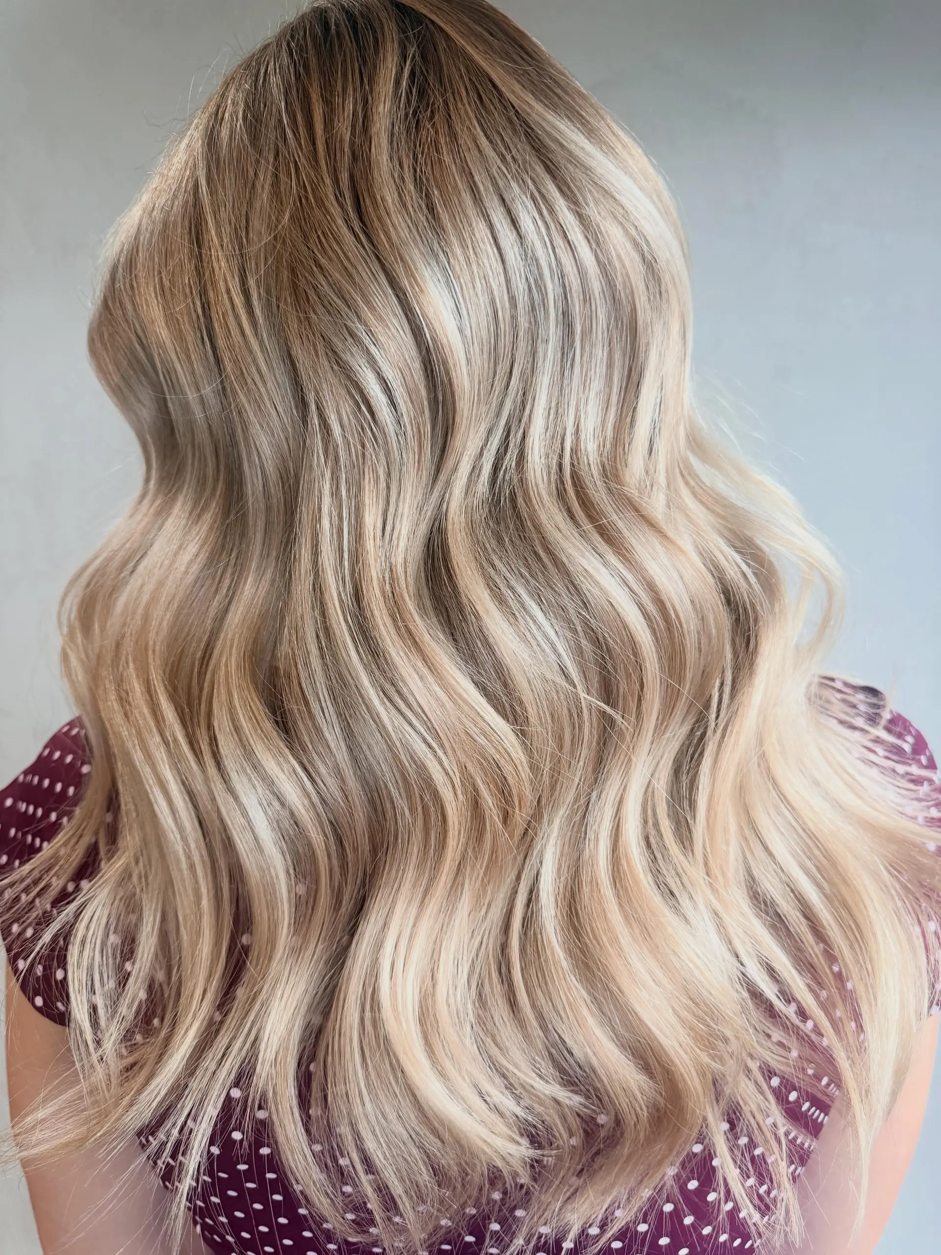 Long, multi-tonal blonde hair styled in soft, loose waves with fine, seamless highlights. 1