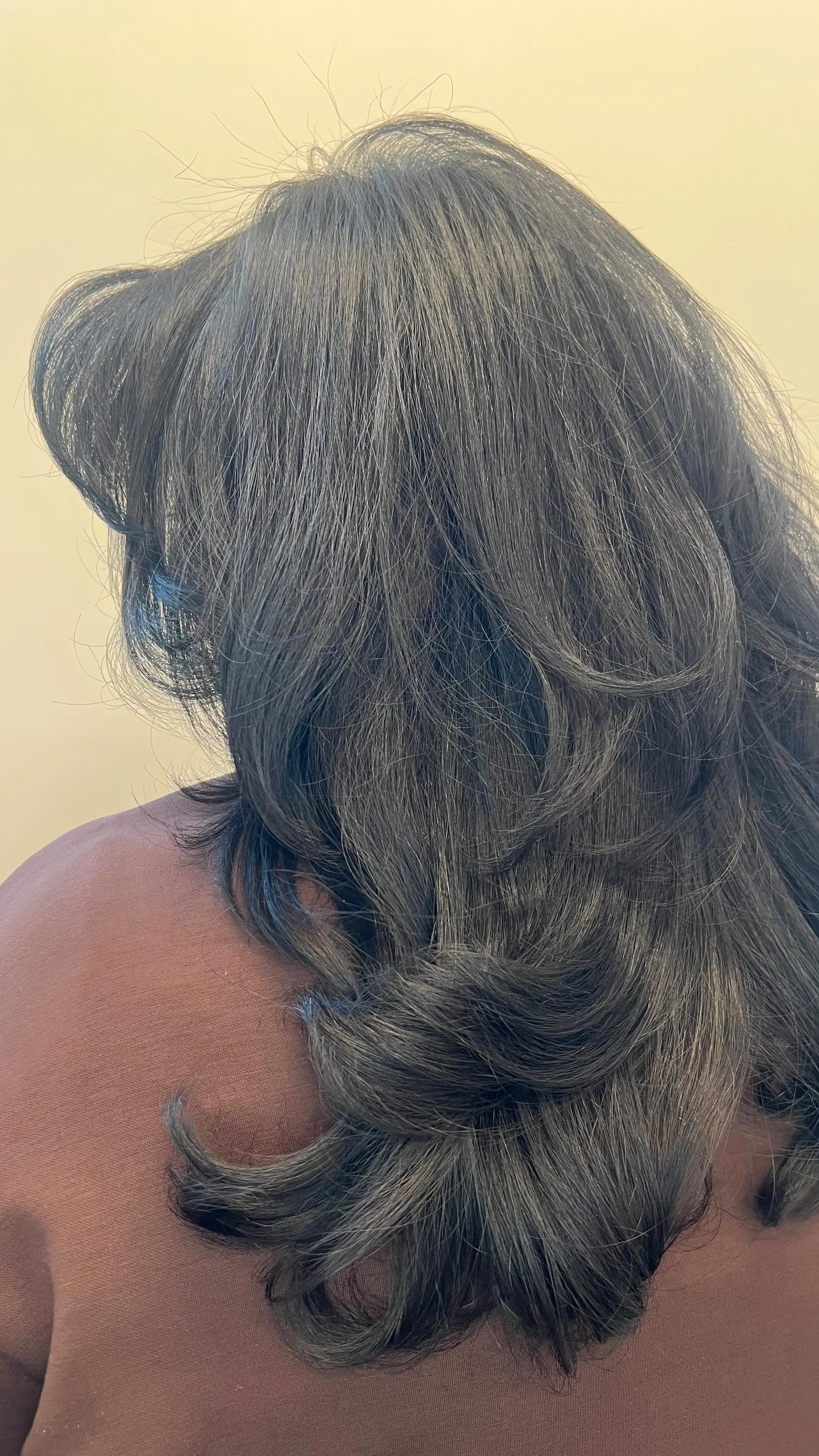 A long, dark layered haircut styled with a soft, voluminous blowout and curled ends. Current Haircut option: $140 before tax. Haircut and included finish only; color is not included. 1