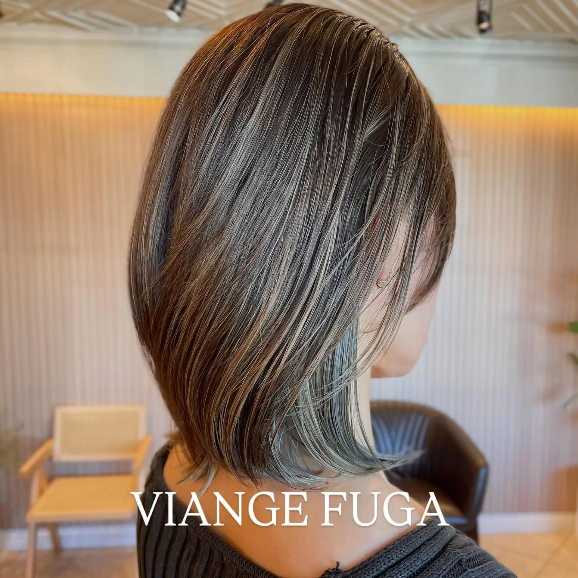A textured neck-length bob featuring finely blended cool-toned blonde highlights over a dark ash base with subtly flipped ends. 1
