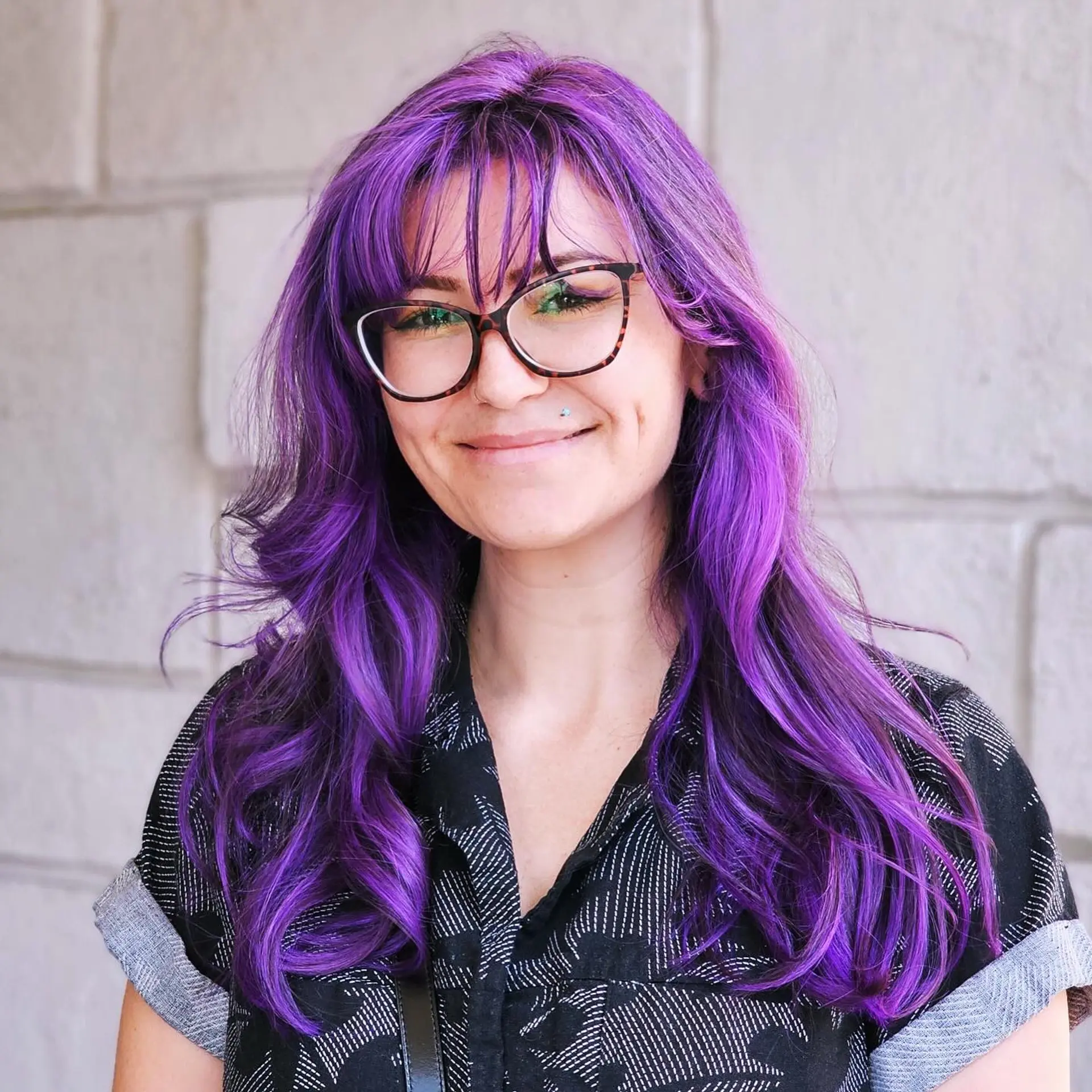 Vibrant all-over purple hair styled in soft, loose waves with wispy face-framing bangs. 1