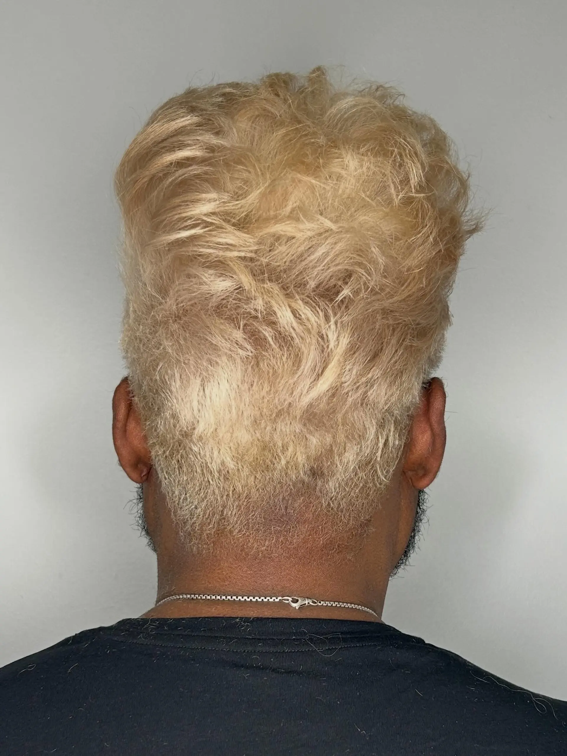 A short, voluminous textured cut styled upwards with a tapered neckline, finished in an all-over bleached platinum blonde tone. 1