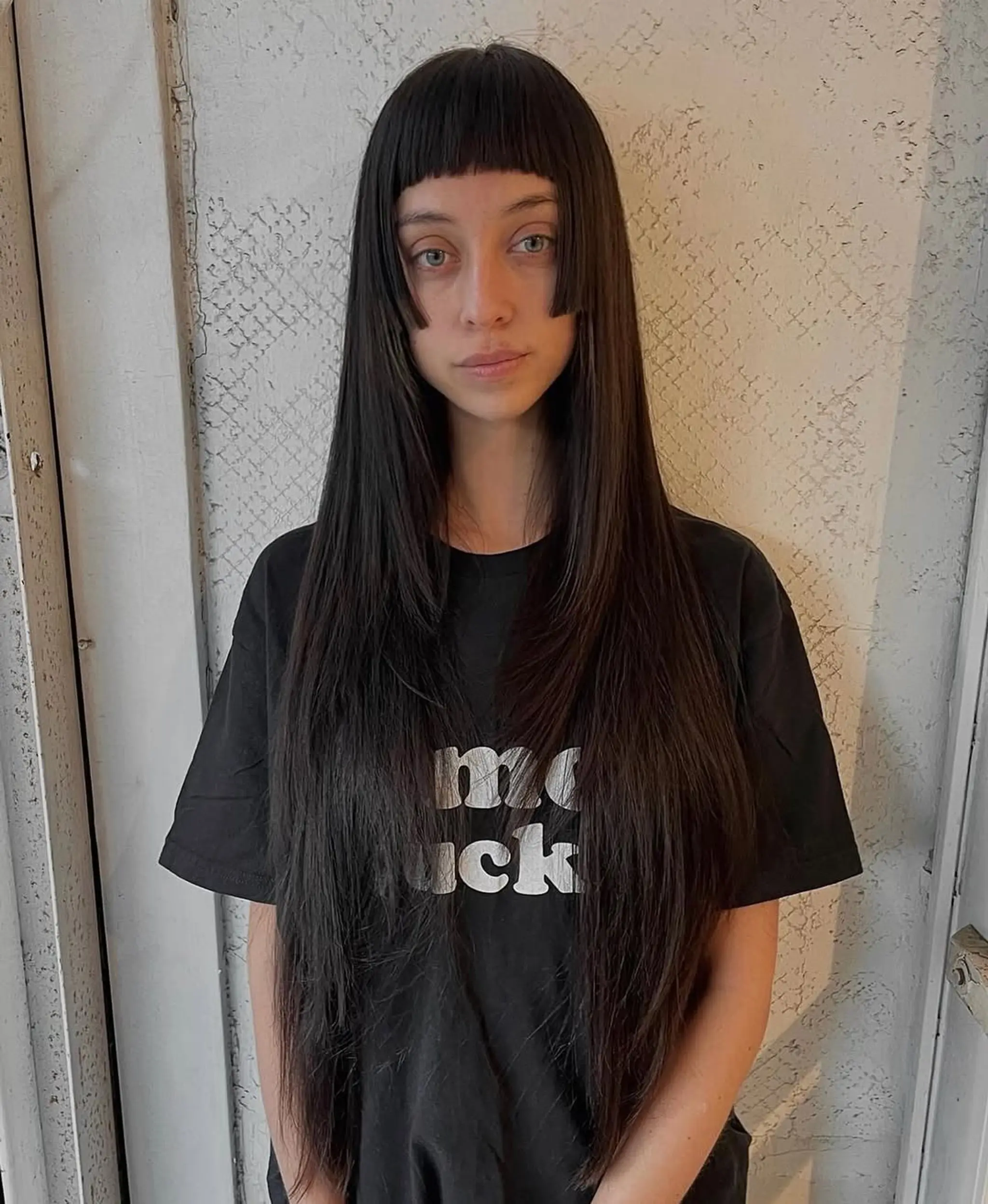 Very long, straight black hair with blunt bangs, sleek and polished.