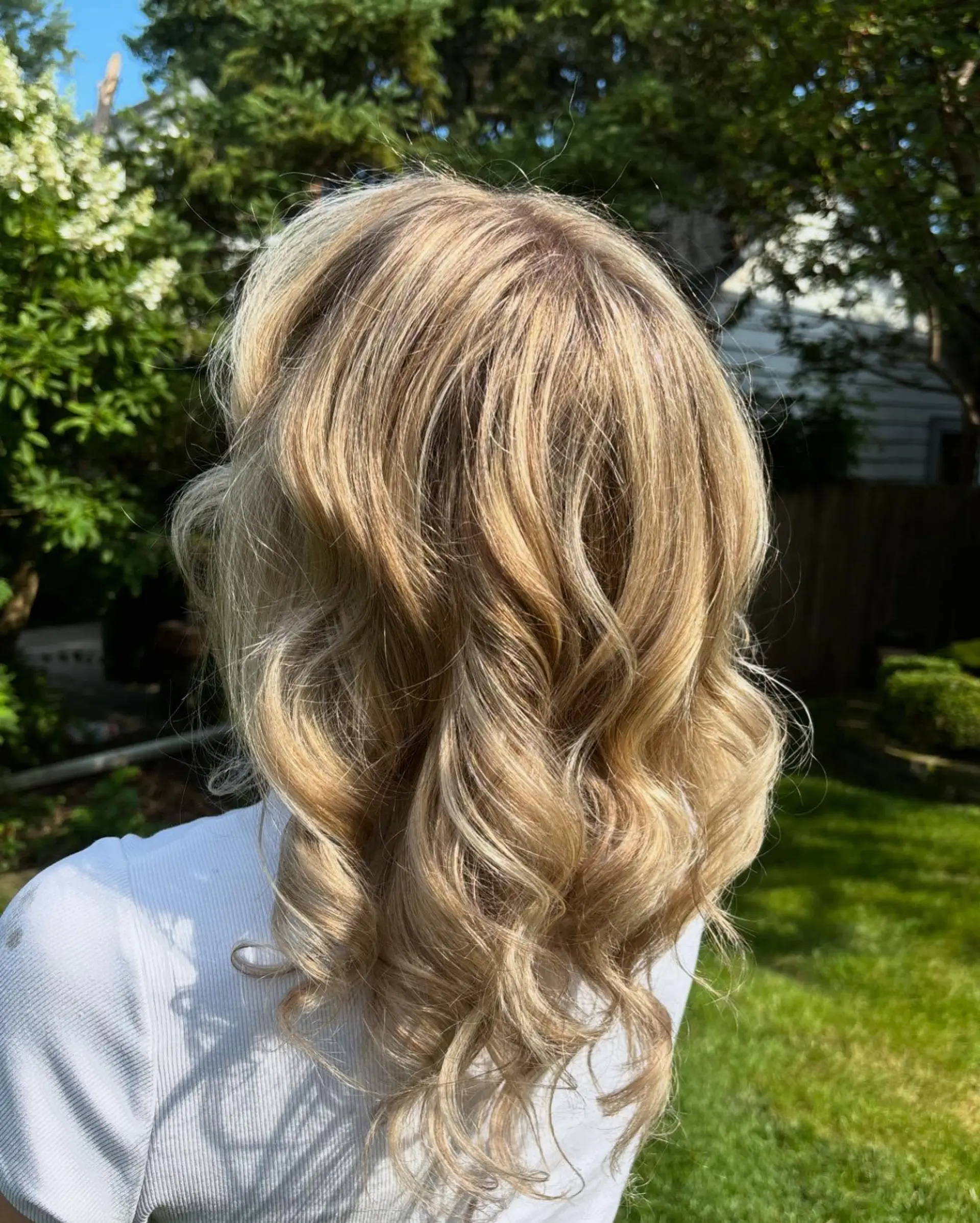 Medium-length blonde hair featuring dimensional highlights and styled in soft, bouncy waves. 1
