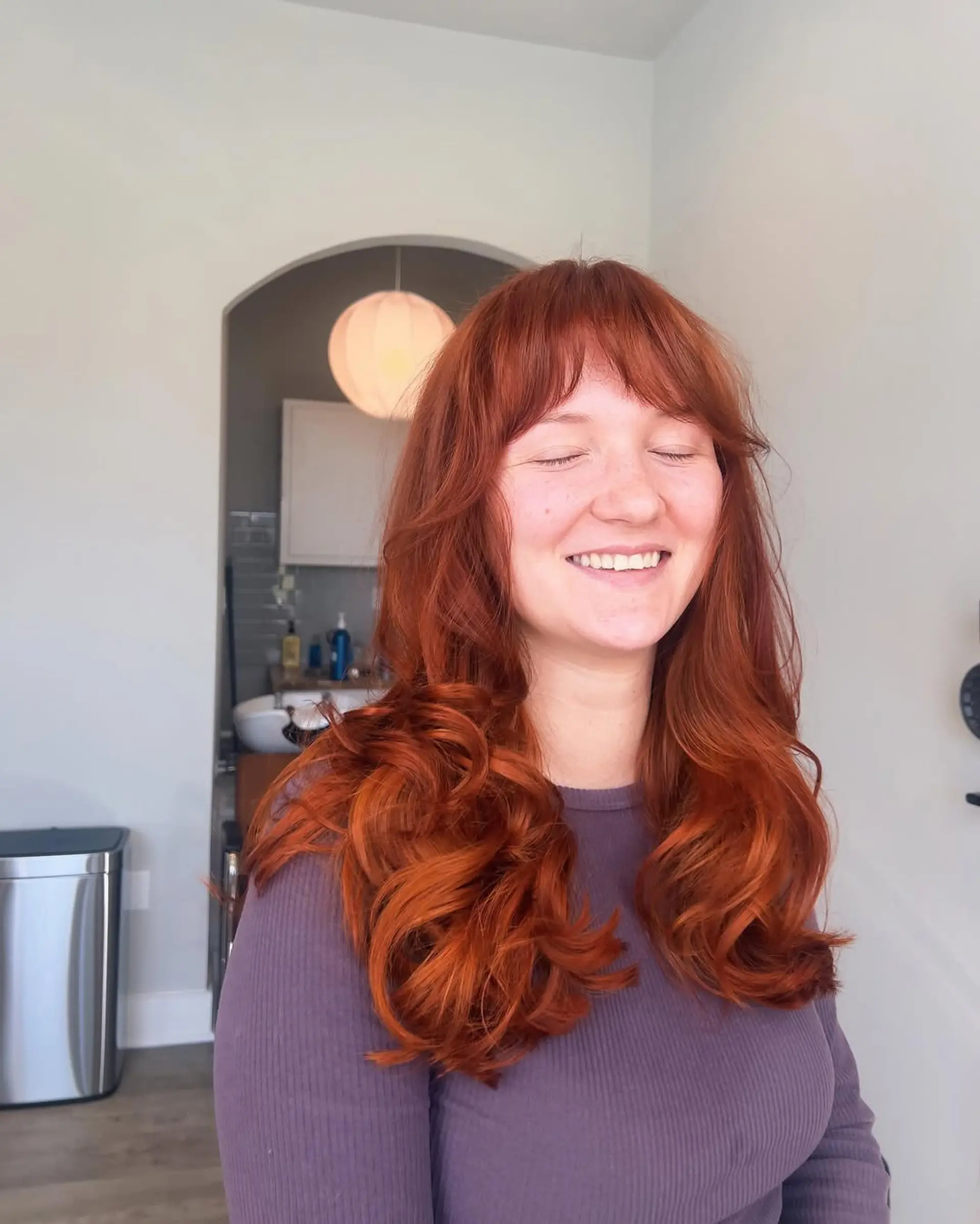Long, wavy hair in a vibrant copper red shade, with a root color application in progress along the part. 4