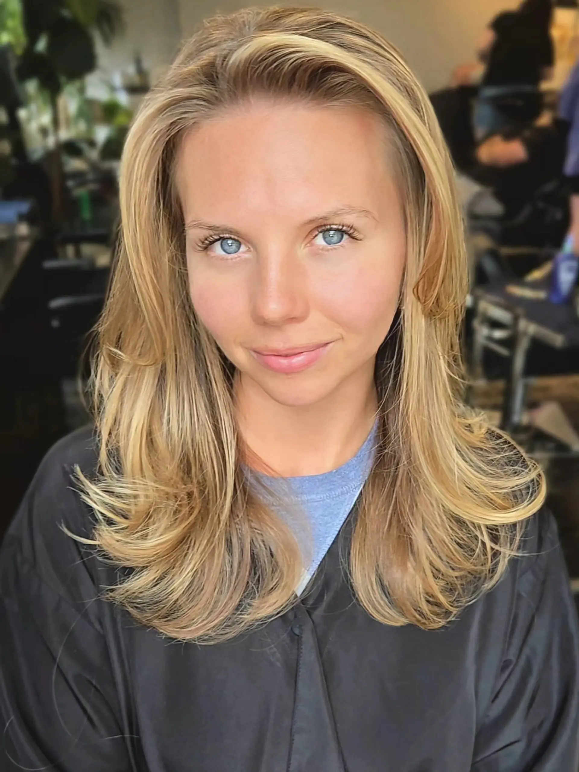 Long golden blonde balayage styled in a bouncy blowout with layered face framing and flipped ends. 1
