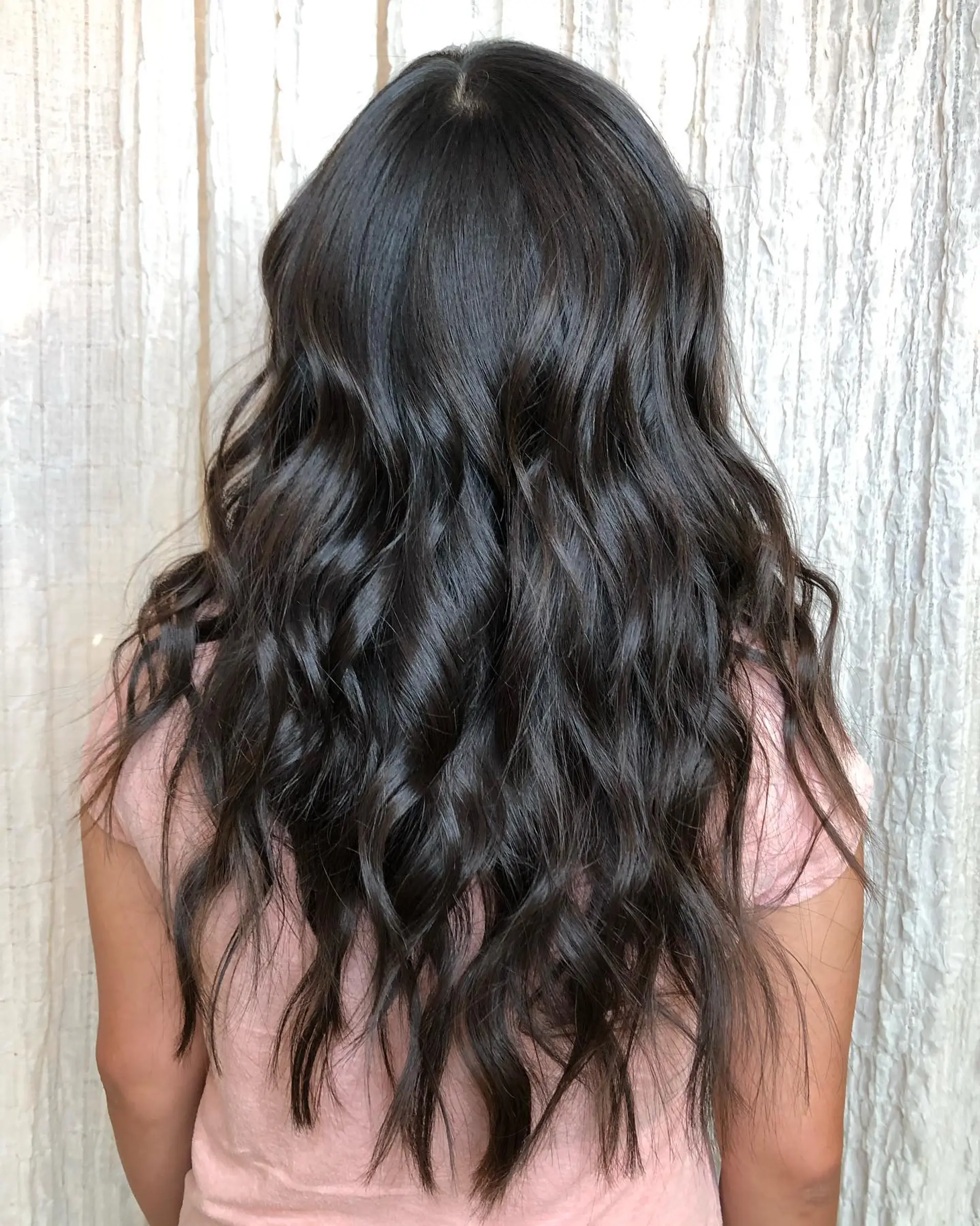 Long, flowing dark brunette hair cut with textured layers and styled into loose, dimensional waves. 1