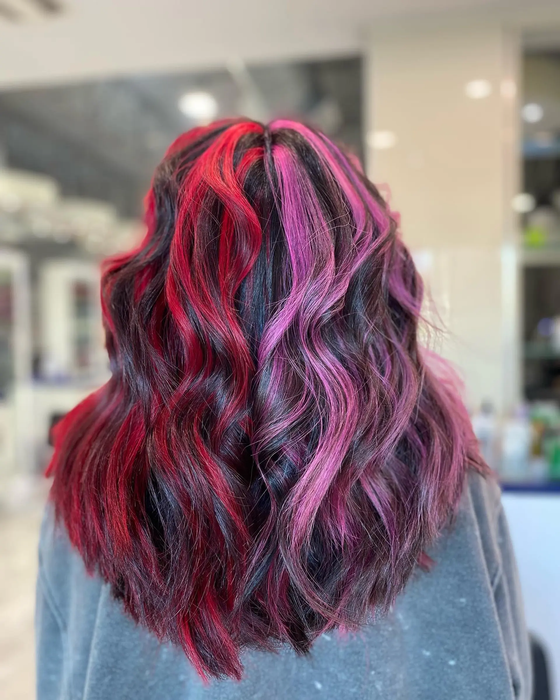 Shoulder-length wavy hair with a striking split dye, featuring a bold pink and red color combination. 2