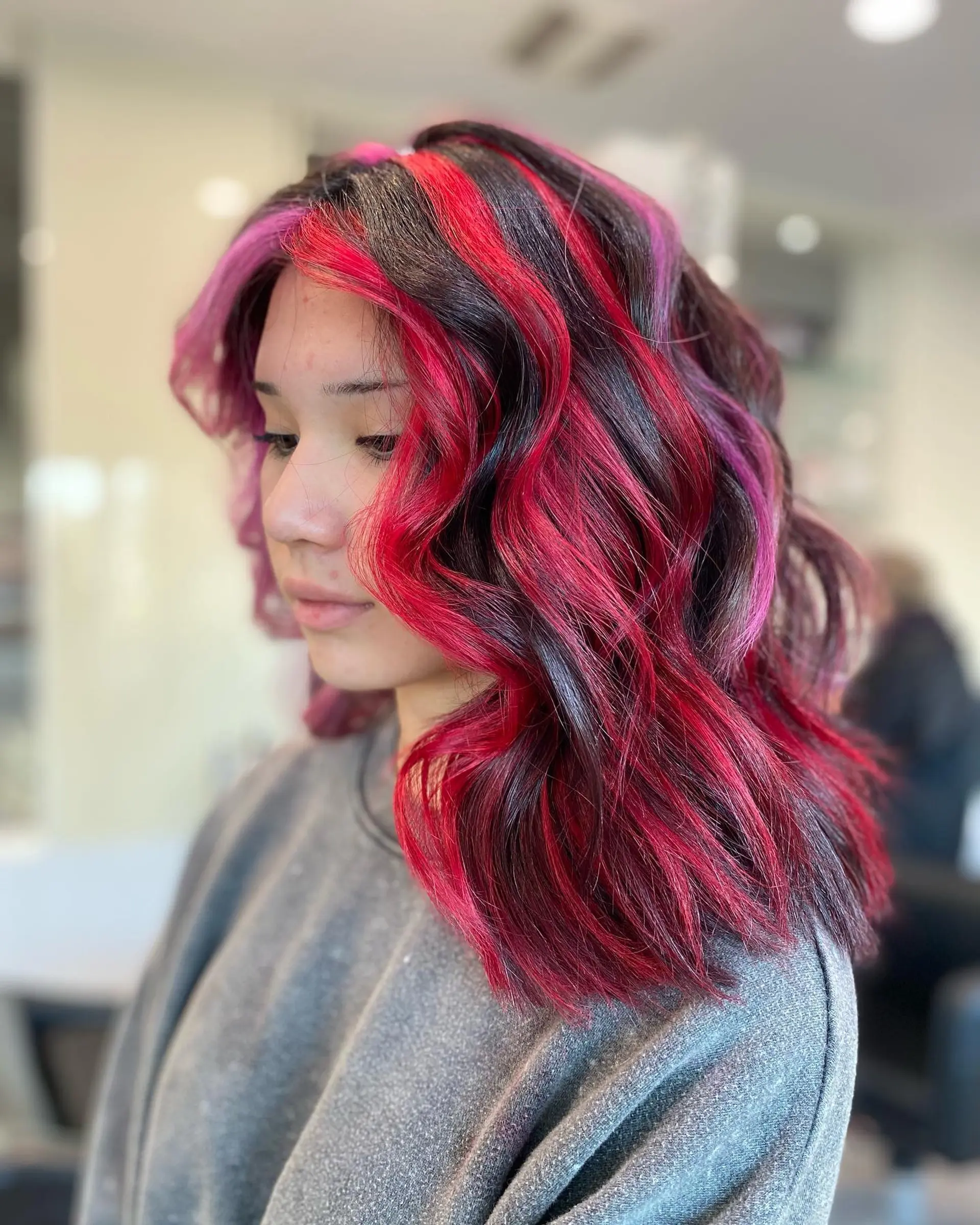 Shoulder-length wavy hair with a striking split dye, featuring a bold pink and red color combination. 3