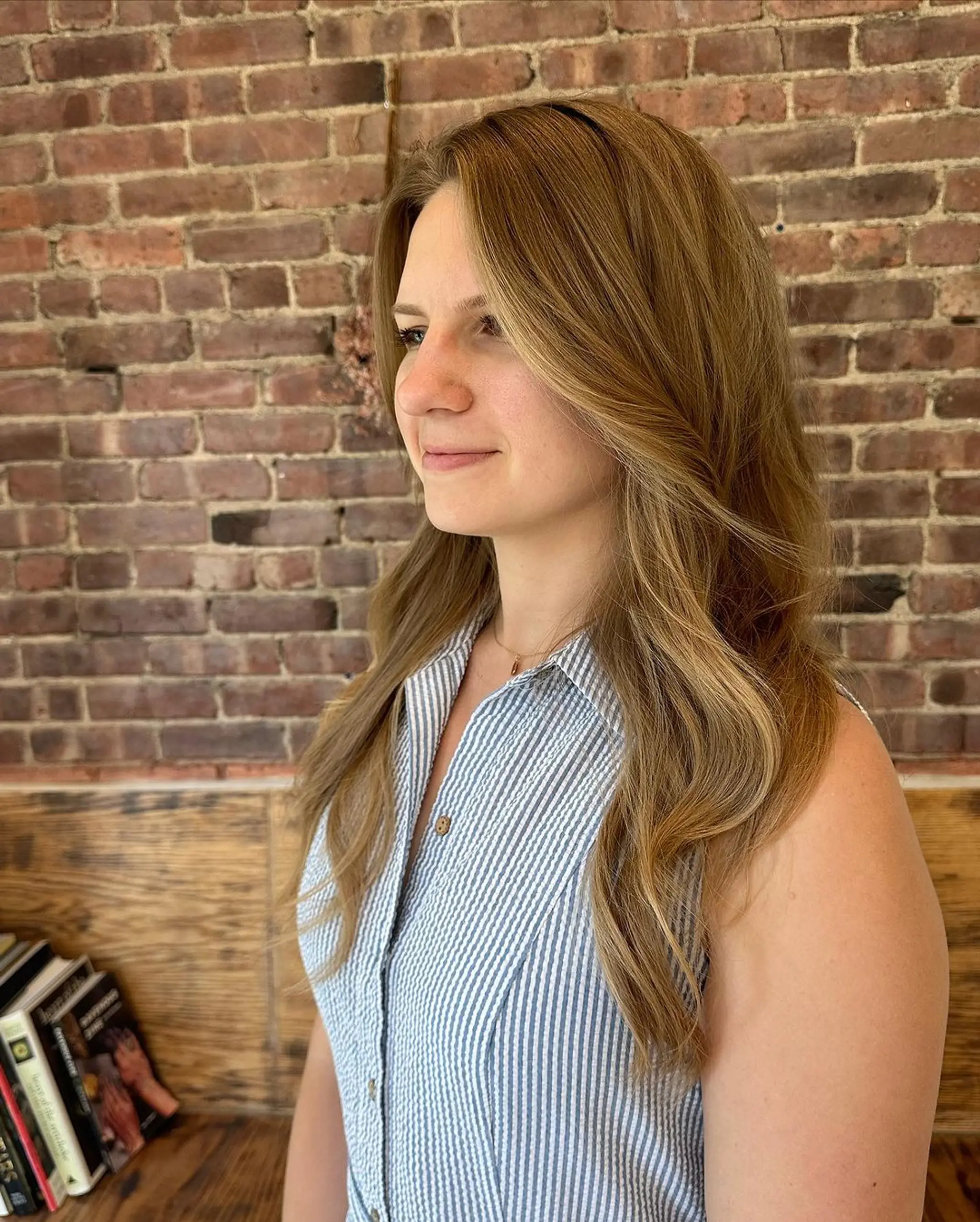 Long, wavy hair with a side part, featuring blonde and light brown hues, natural waves, soft curls, and face-framing layers.