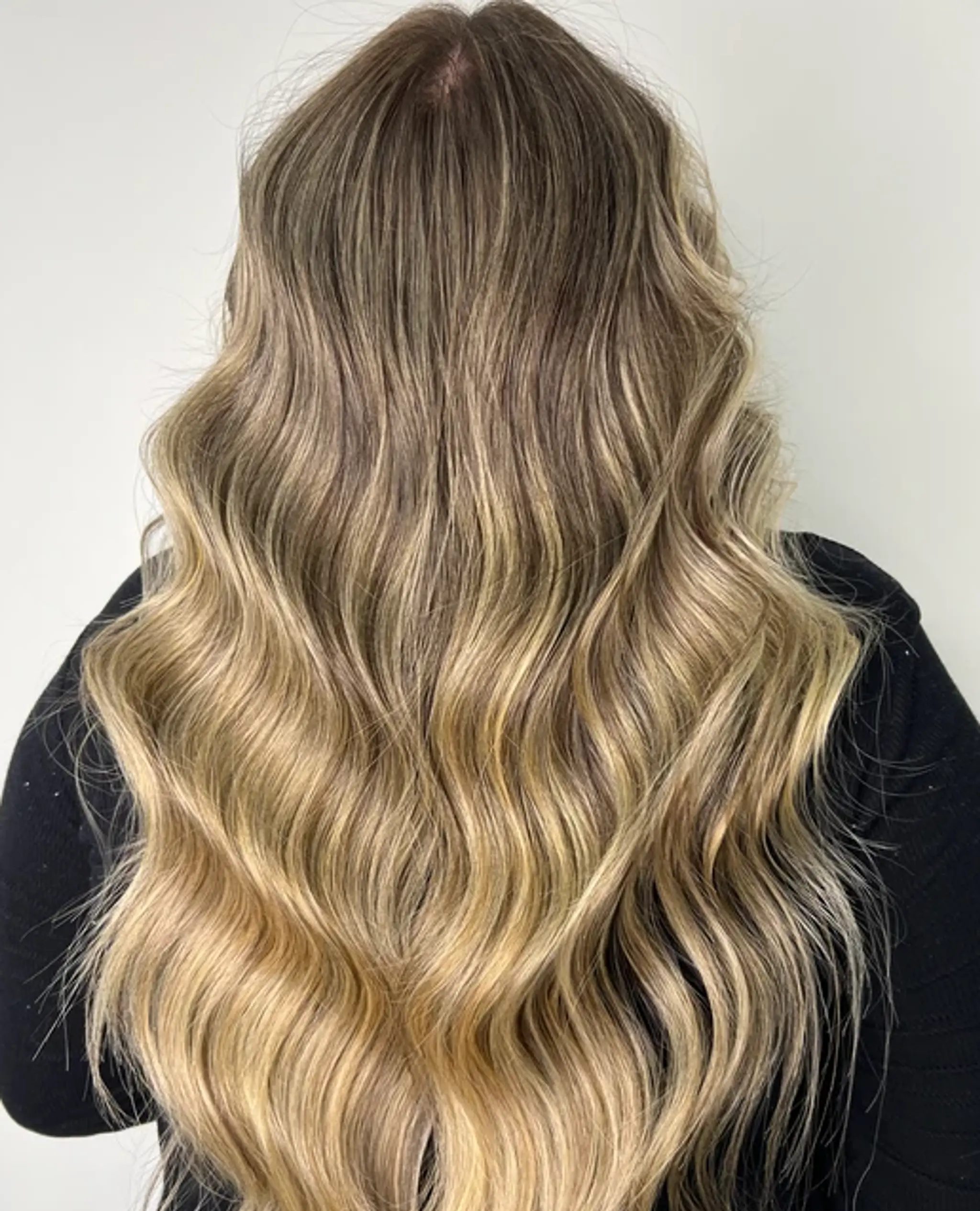 Very long, wavy hair with a honey blonde and ash brown blend, featuring soft, glossy waves and a gradient color transition.