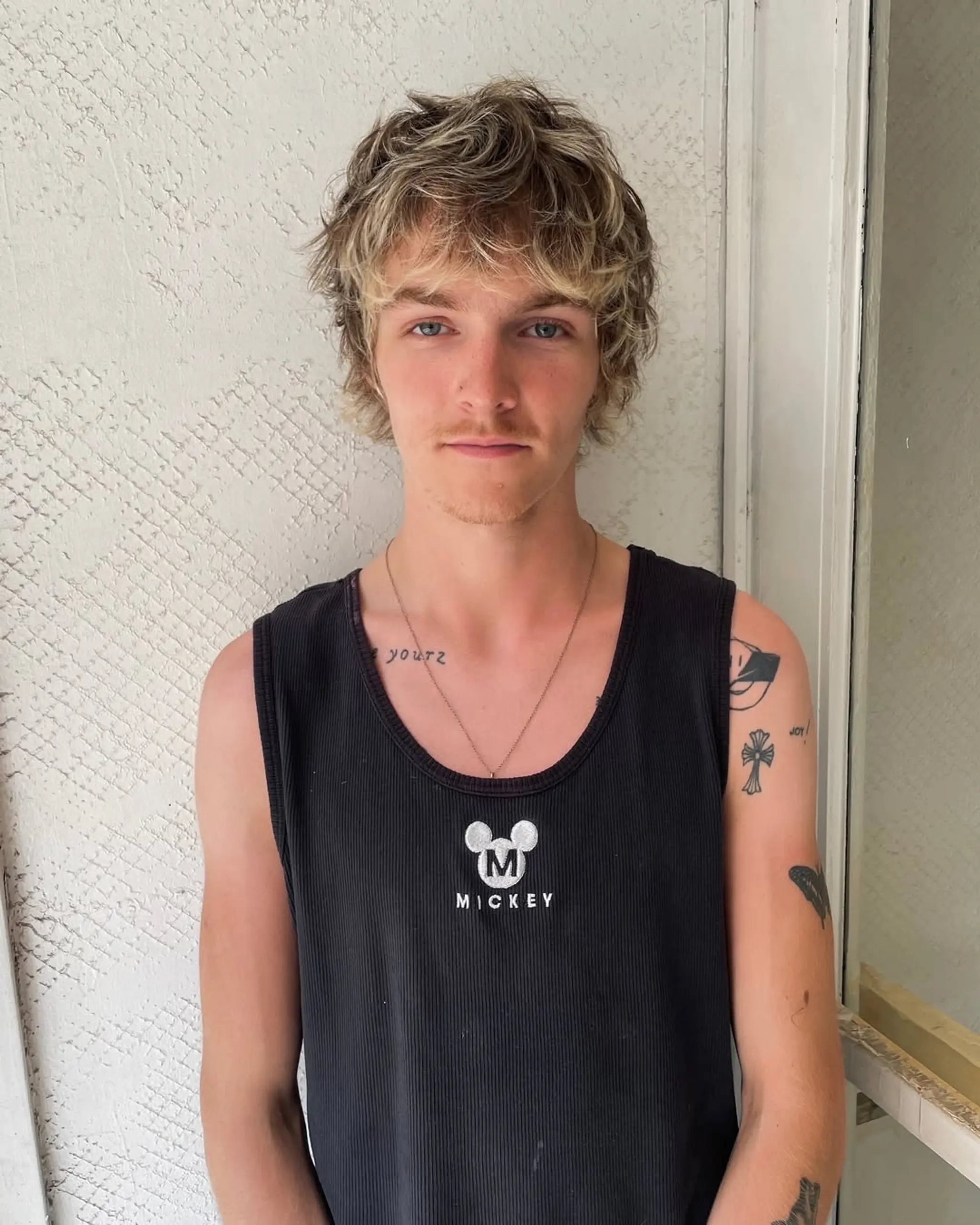 Medium-length, wavy hair with shaggy layers and textured ends in a sun-kissed blonde color, styled in a tousled, casual manner.