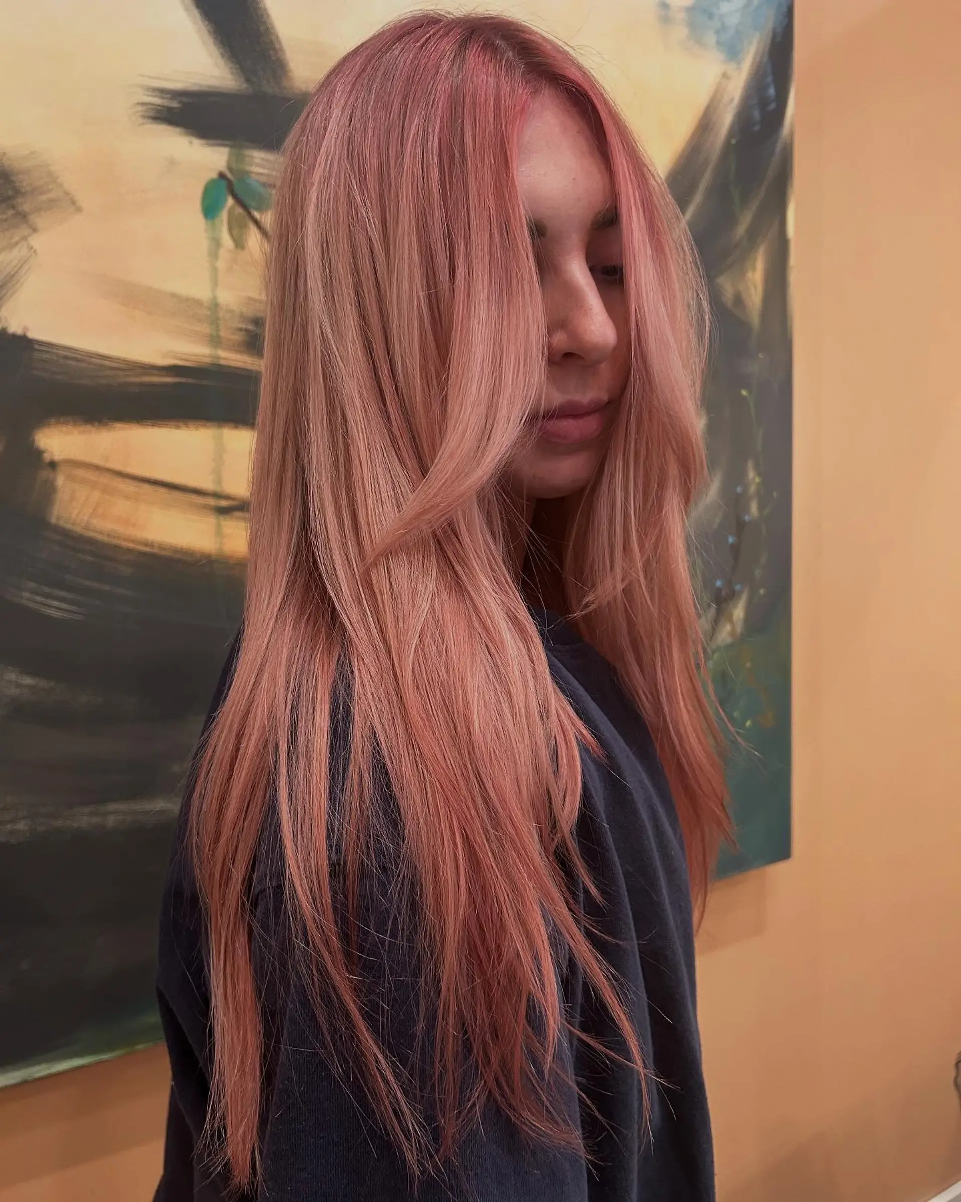 Long straight hair colored in a soft pastel rose gold shade with face-framing curtain layers. 1