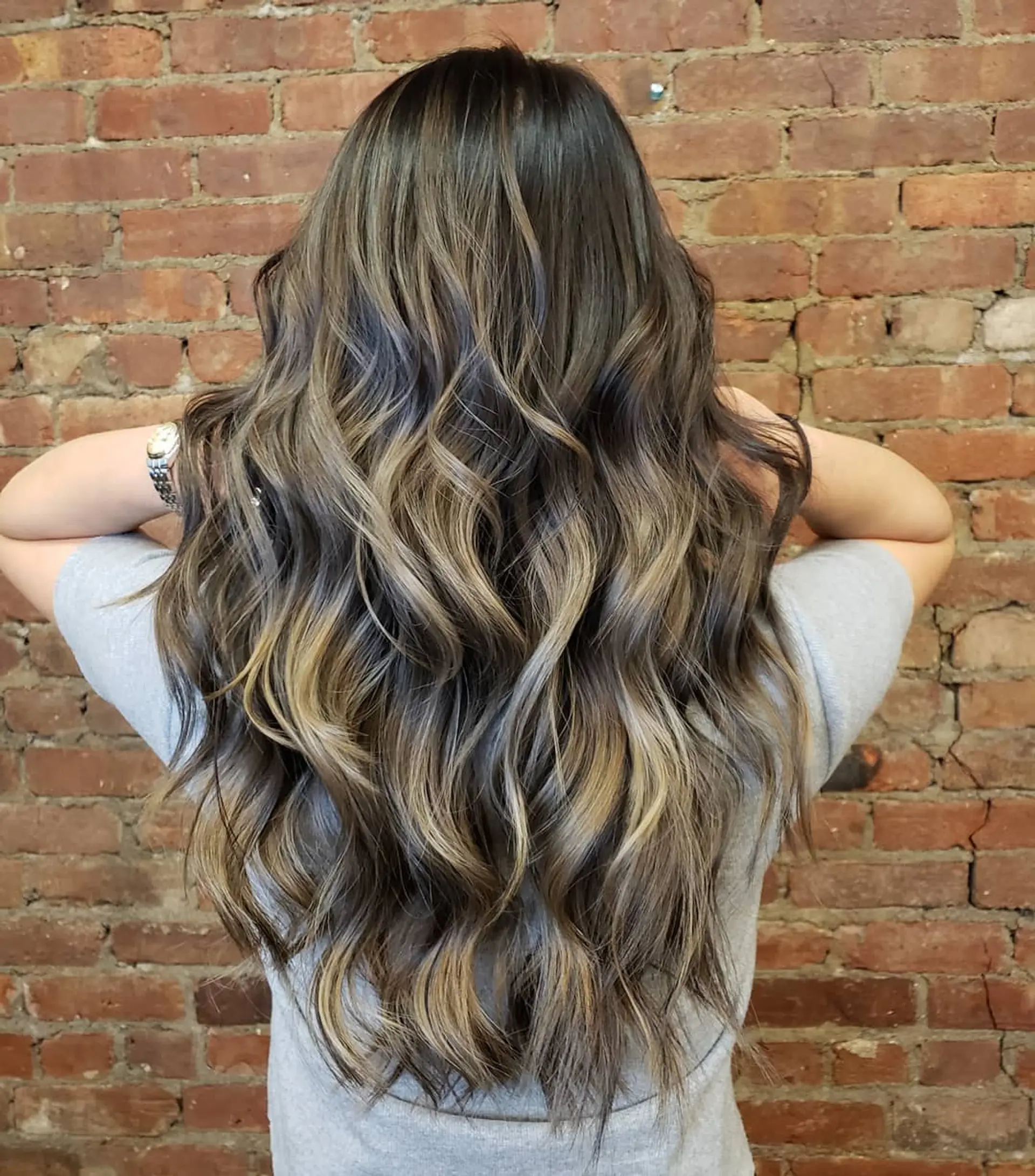 Long, flowing brunette hair with dimensional blonde balayage highlights styled in soft, loose waves. 1
