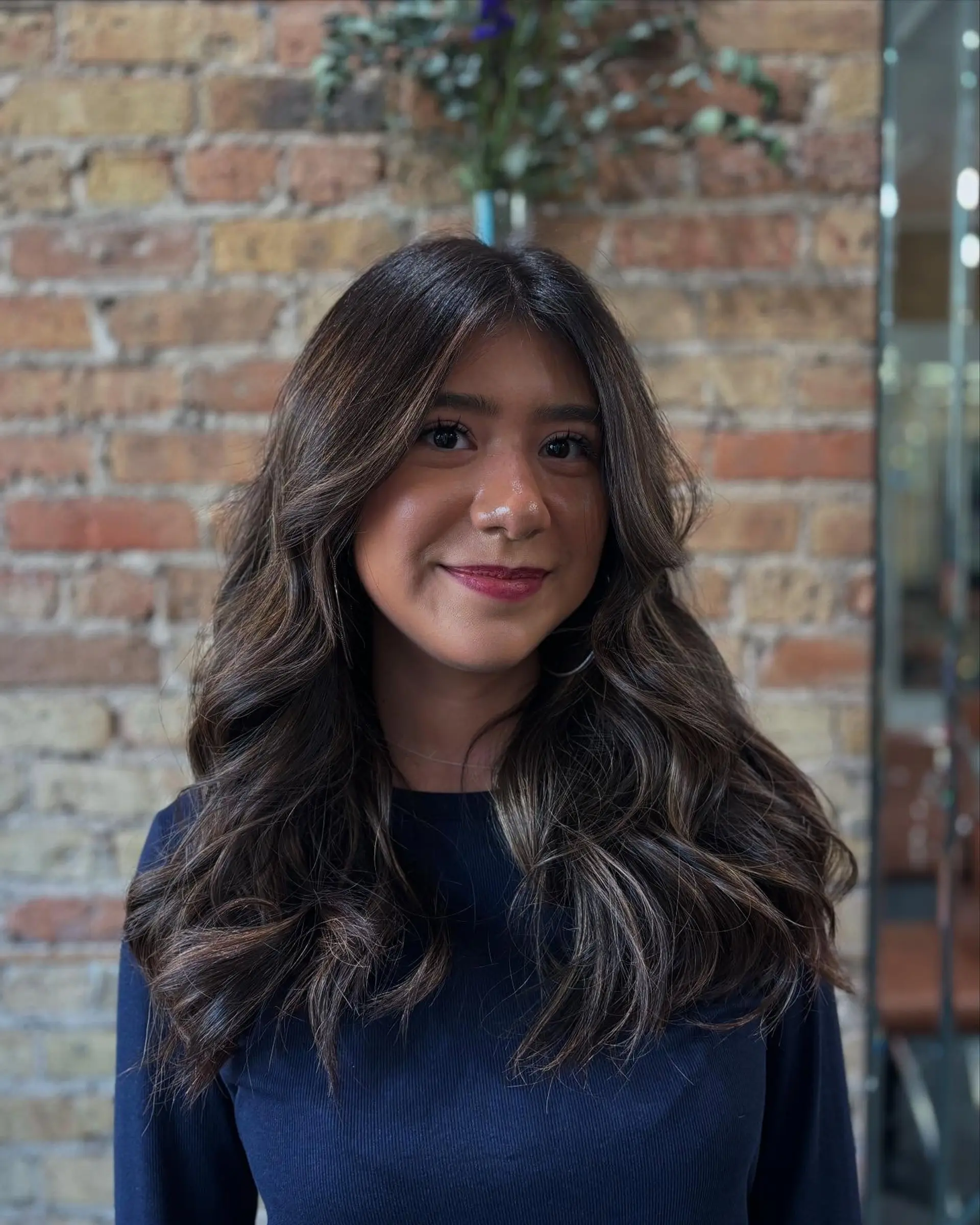 Long dimensional brunette hair styled in voluminous, soft waves with face-framing layers. 1