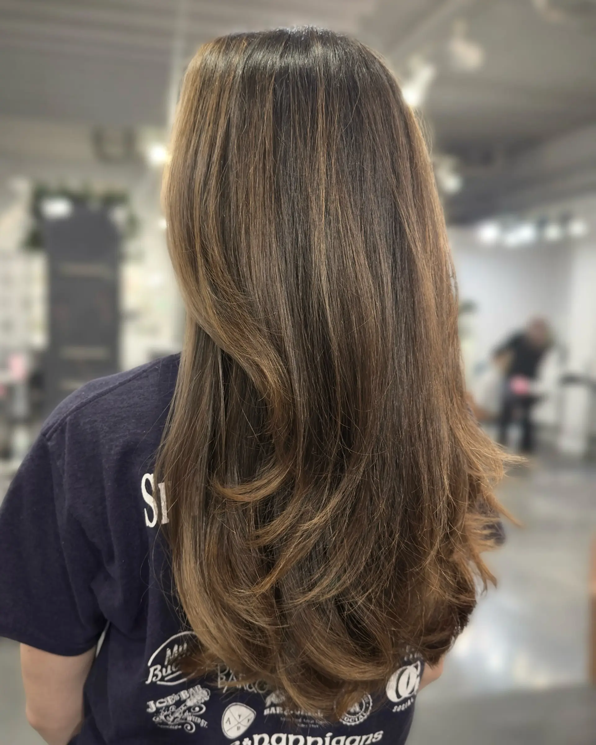 A long, straight brunette hairstyle with dimensional color and layered haircut. 2