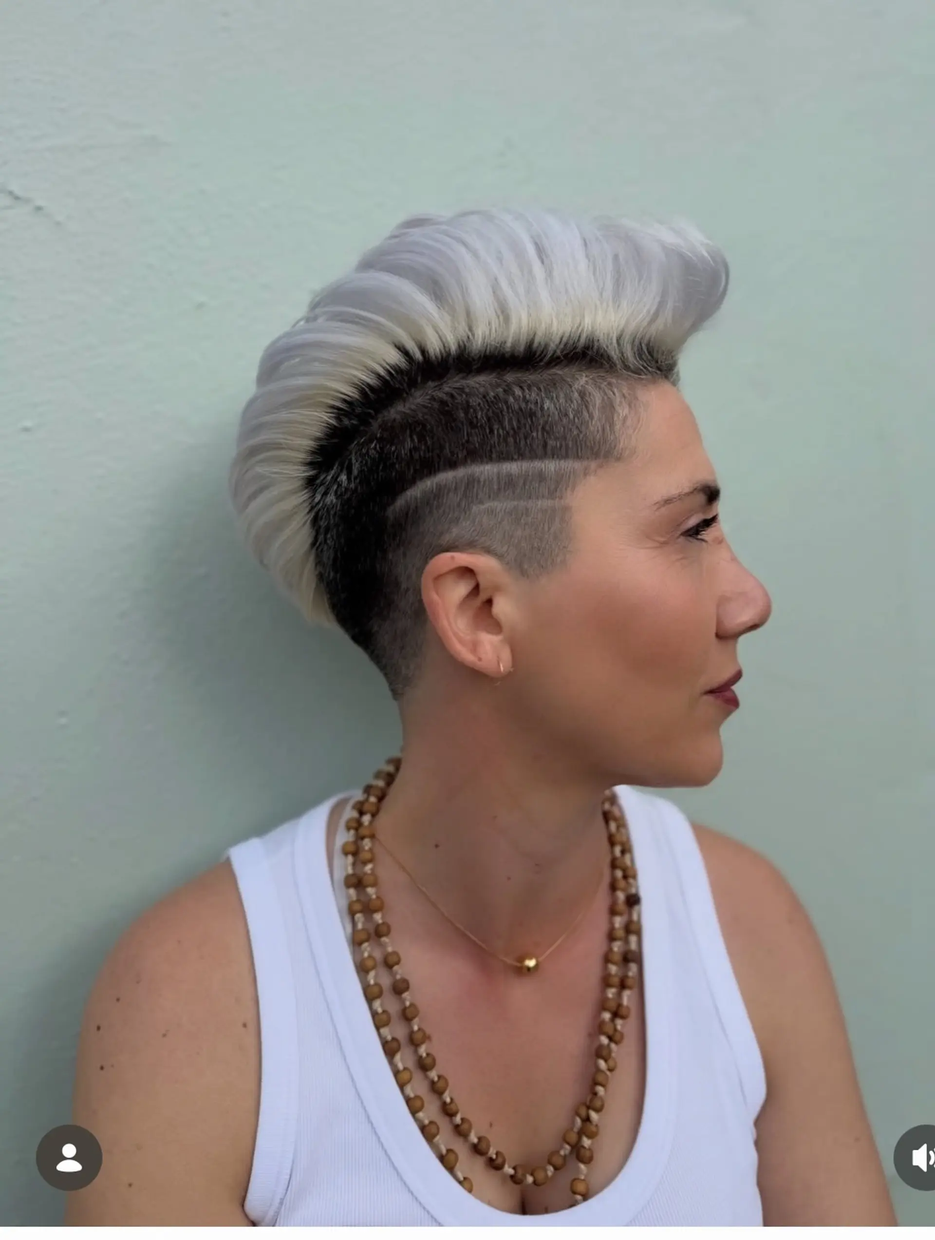 A bold short hairstyle featuring closely faded sides with a shaved line accent and a high-volume platinum mohawk. 1