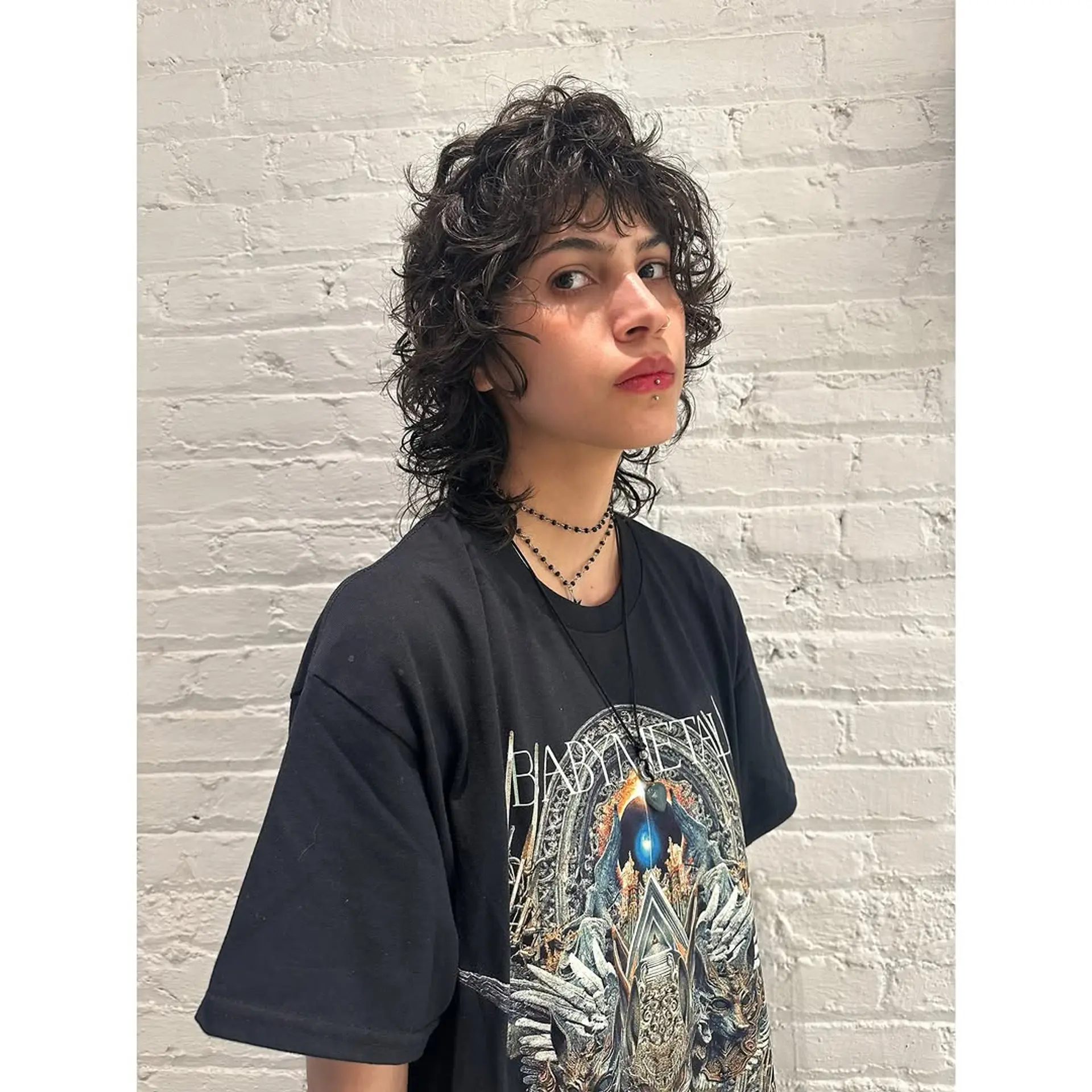 A trendy and edgy medium-length curly shag mullet with bangs and lots of layers. 1