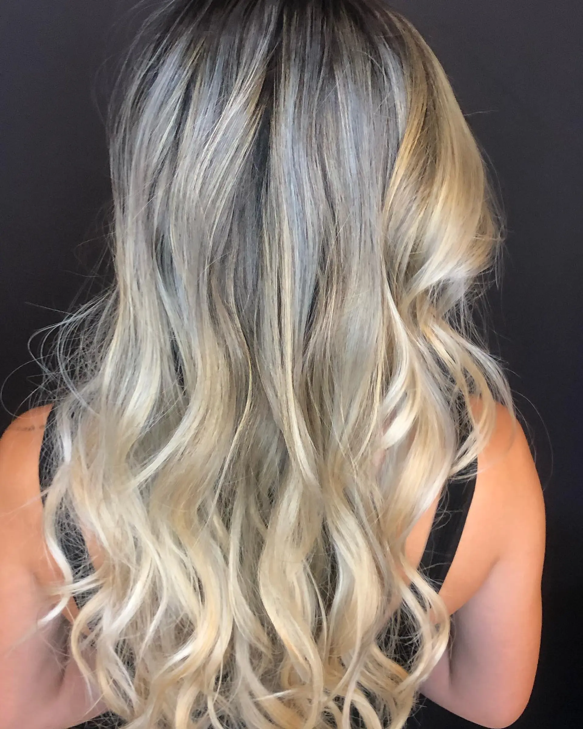 Long wavy hairstyle featuring a soft root smudge seamlessly blending into dimensional cool blonde balayage ribbons. 1