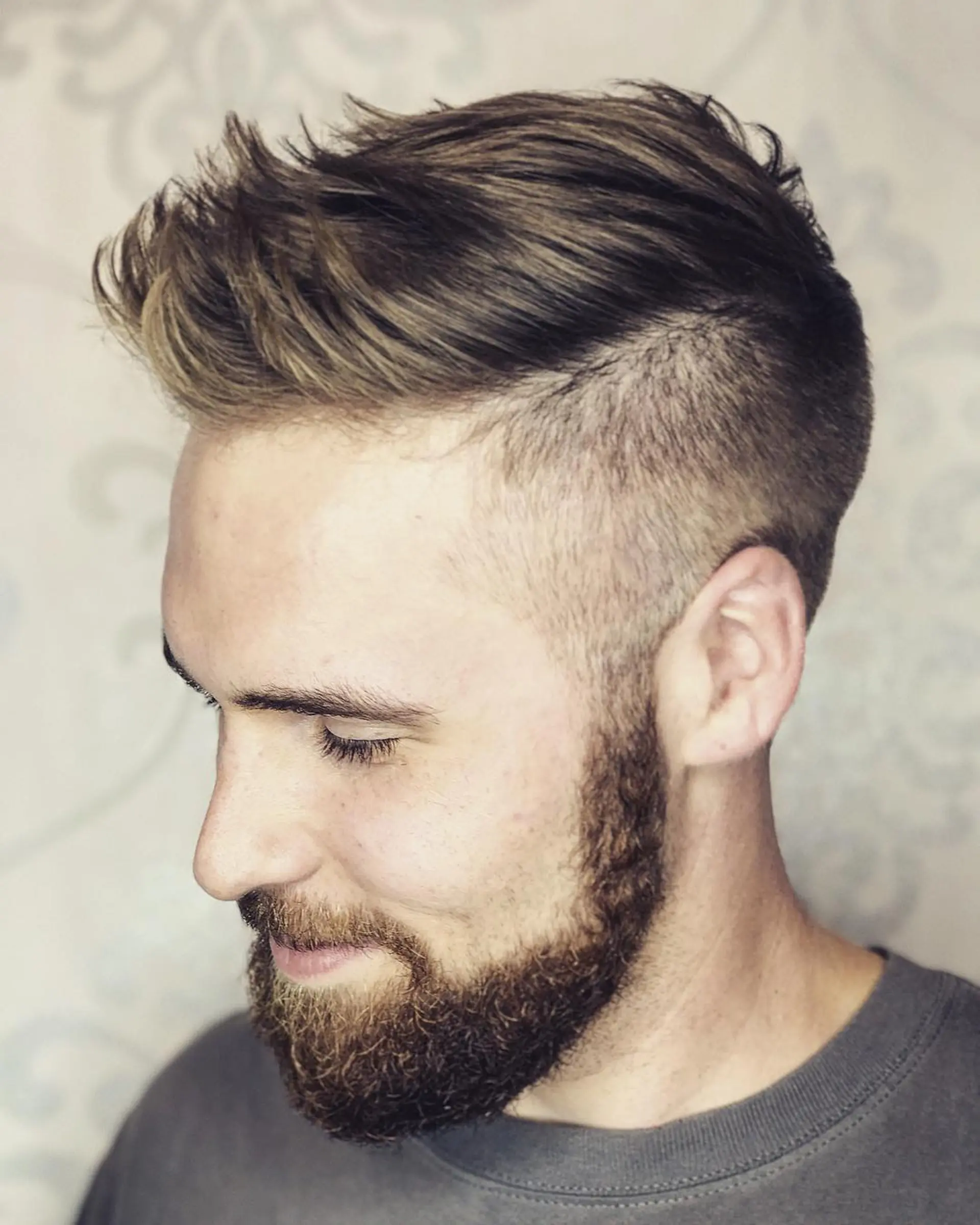 A modern men's disconnected undercut with short clippered sides and a textured, sweep-back top. 1