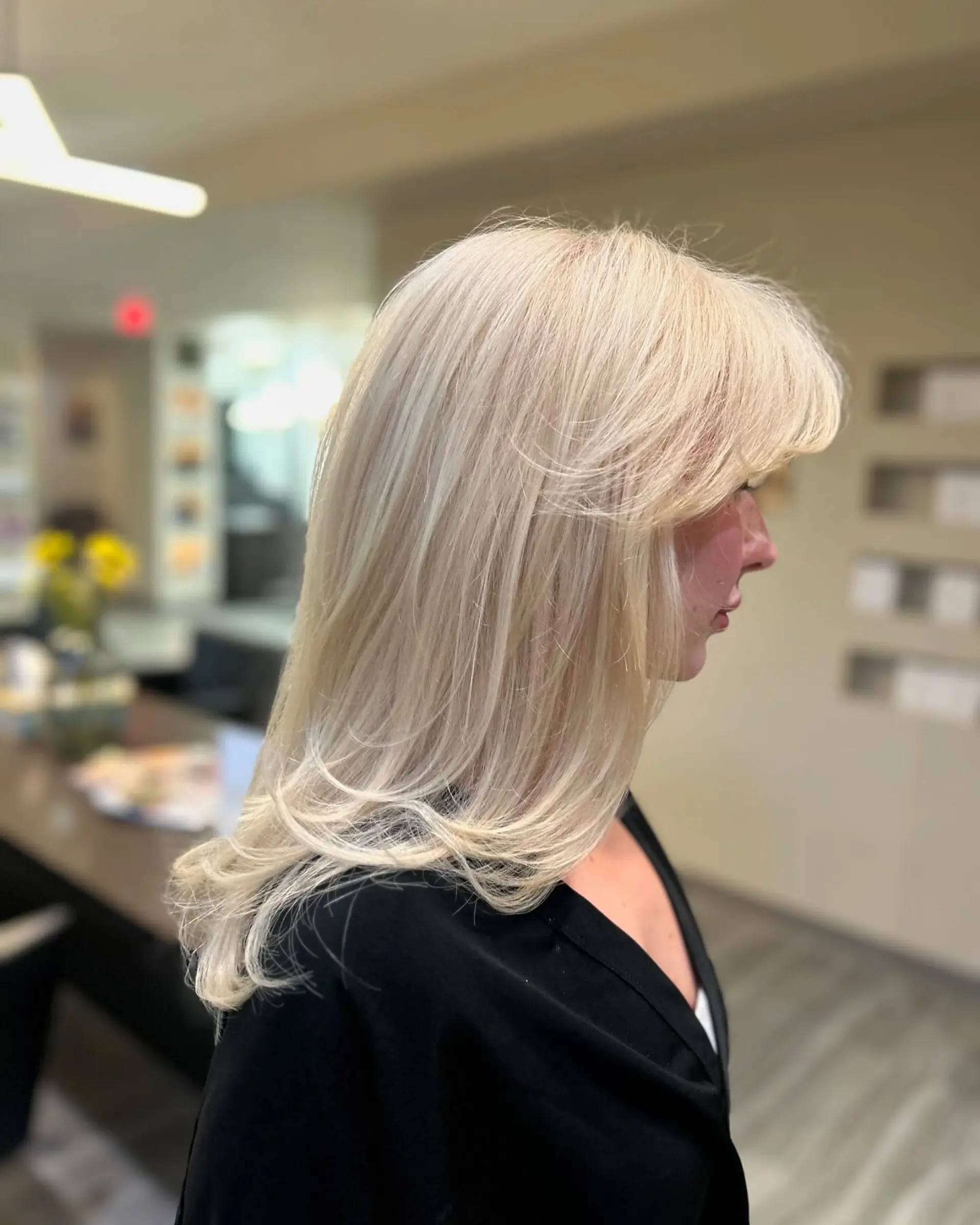 Luminous all-over platinum blonde styled in a smooth, voluminous blowout with sweeping face-framing layers. 1