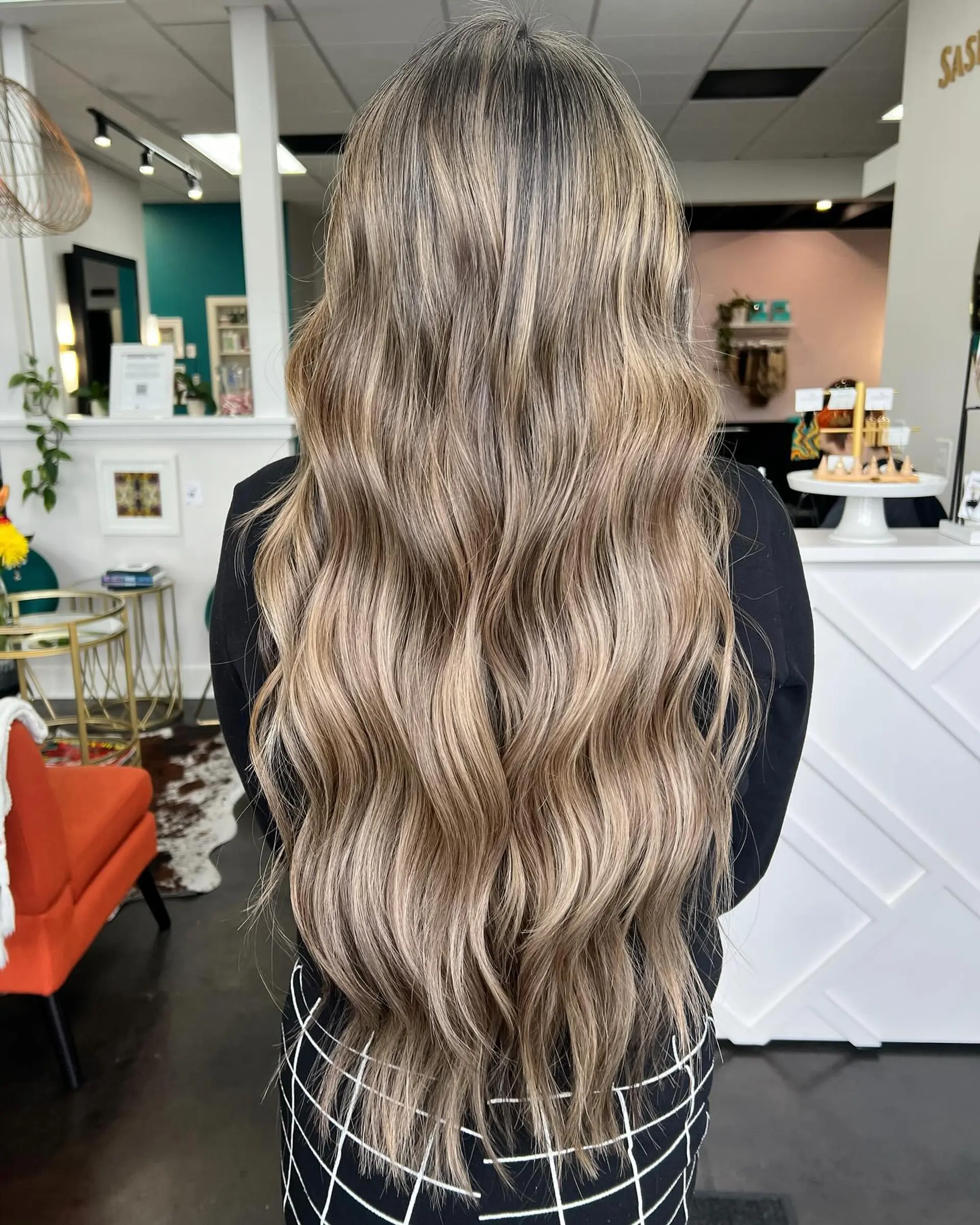 Extra-long hair styled in loose waves, showcasing a seamless dimensional ash and beige blonde balayage over a soft light brown base. 1