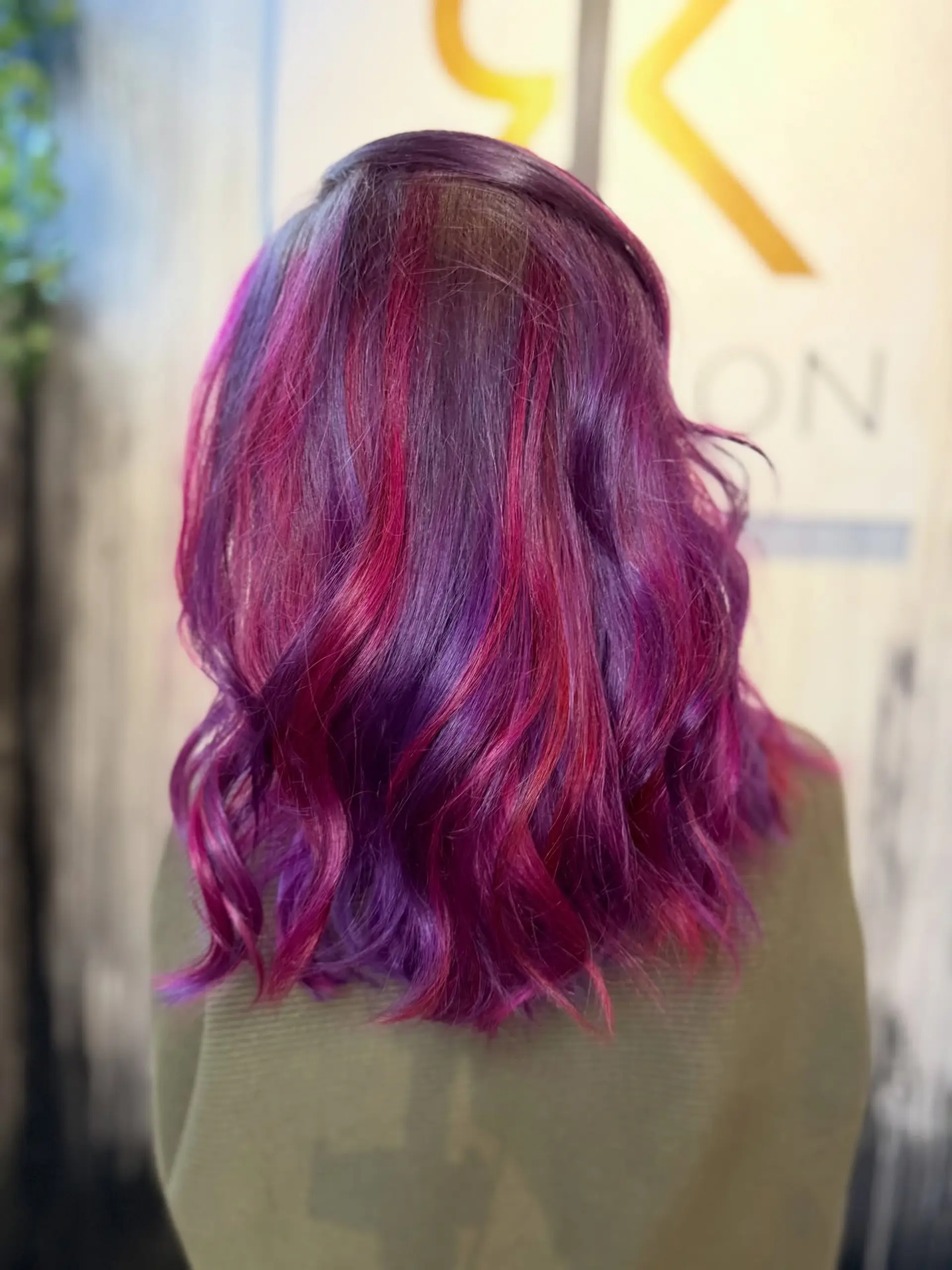 Shoulder-length hair colored in multidimensional shades of vivid purple and magenta, styled with loose textured waves. 1