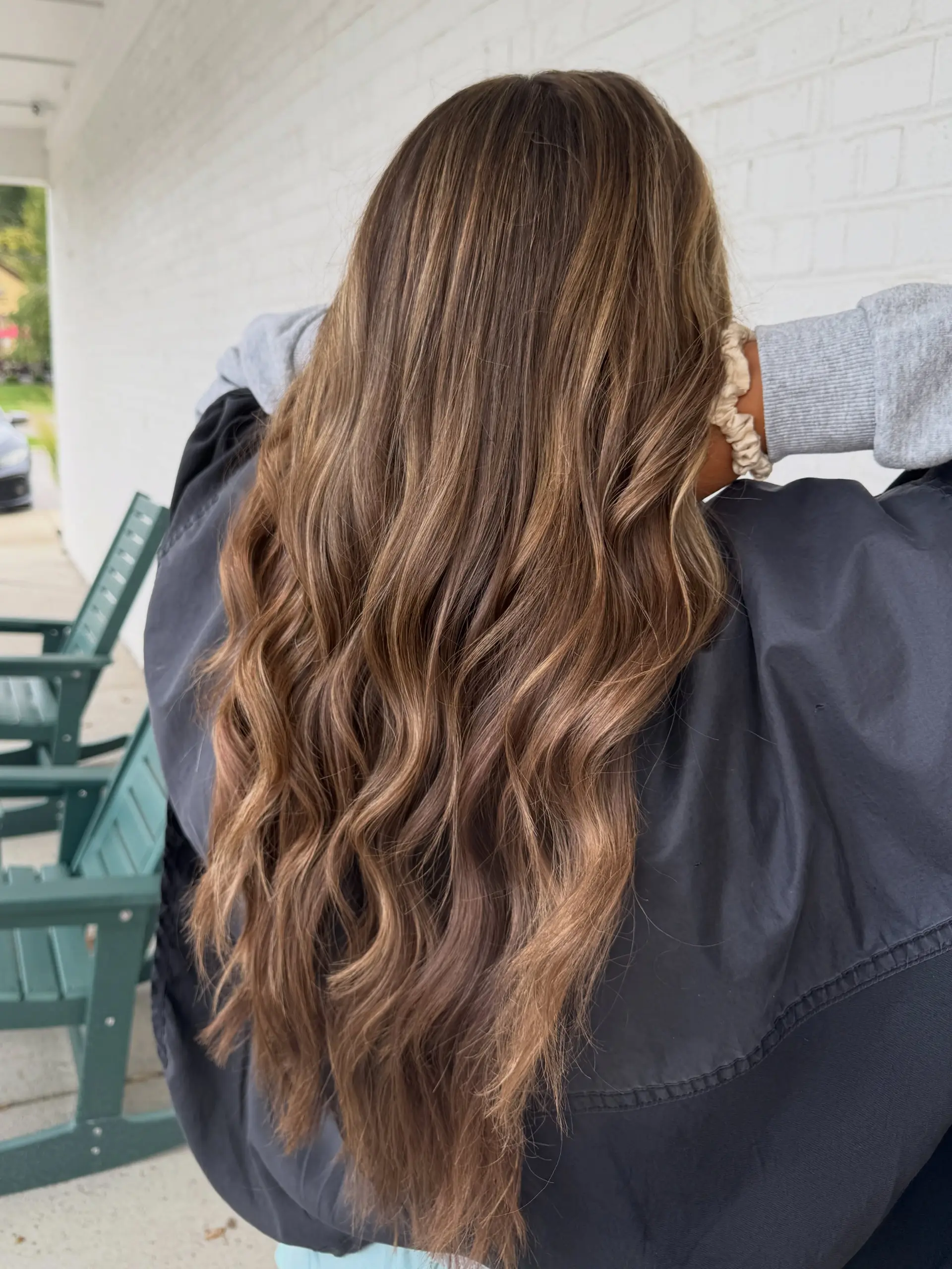 Long dimensional brunette hair with soft caramel balayage highlights styled in gentle, cascading waves. 1
