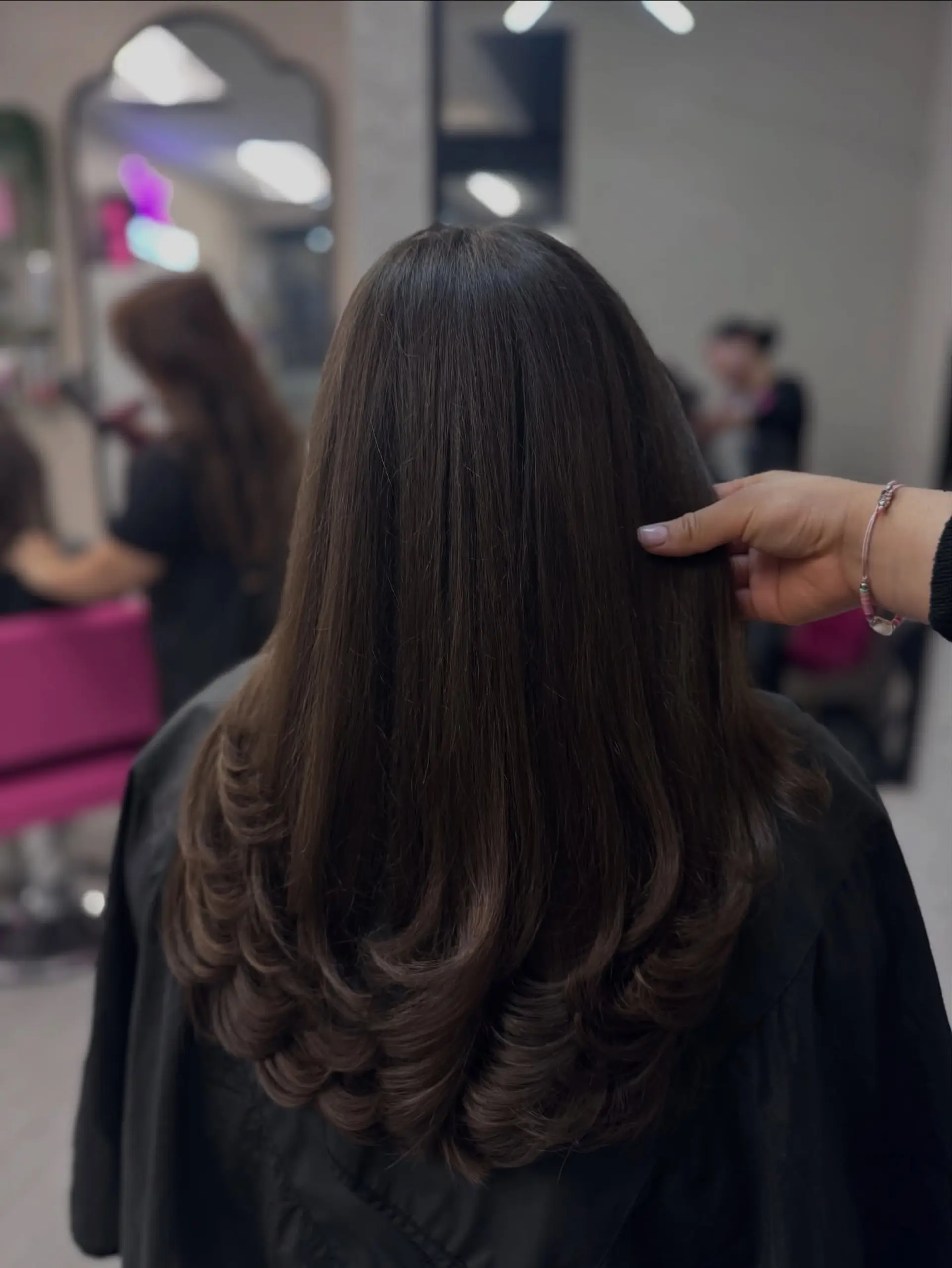 A sleek, long dark brown haircut cut in seamless cascading layers, styled with bouncy, rounded inward-curled ends. 1