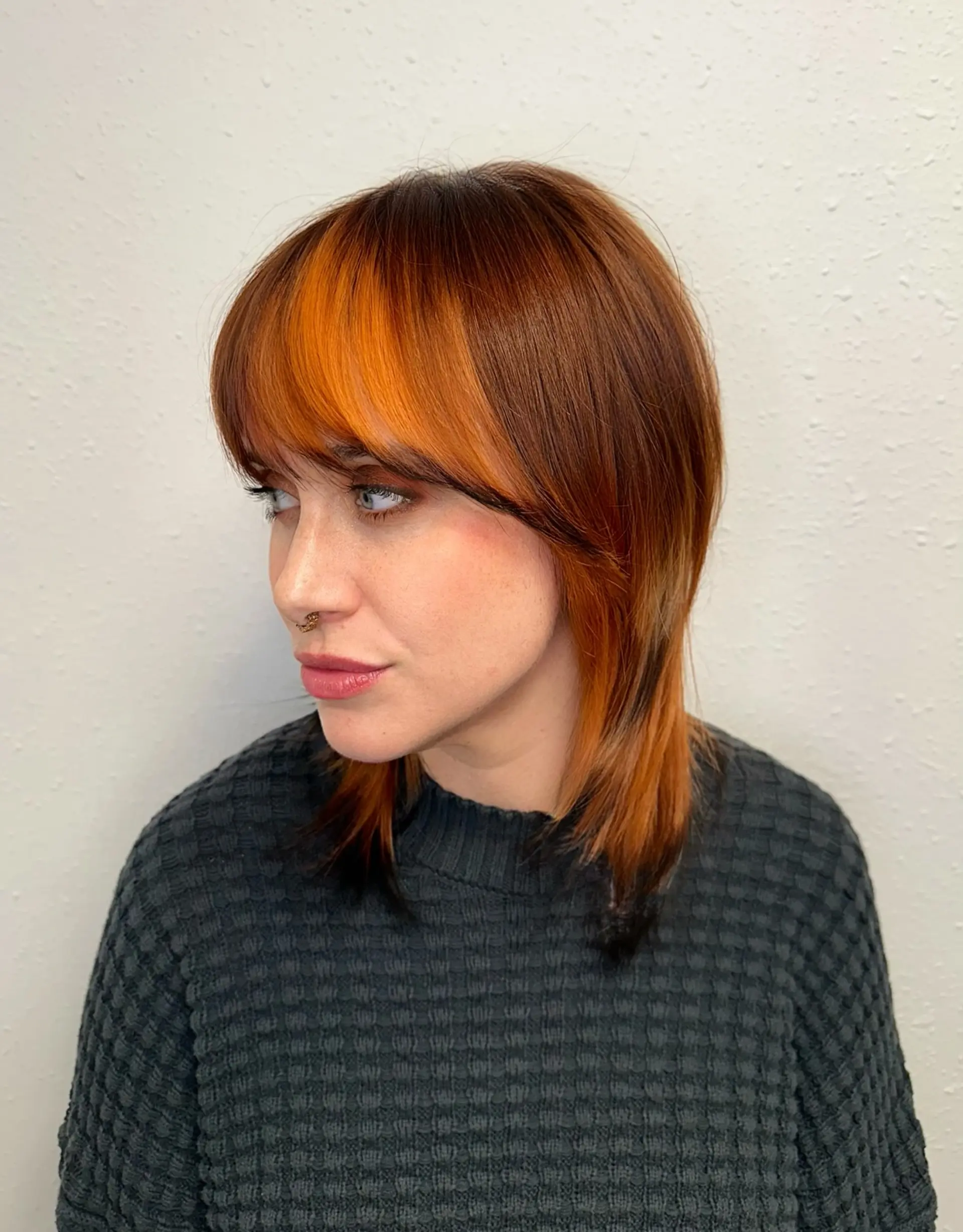 A layered medium-length shag with full bangs, featuring a vibrant fox-tail copper tone contrasted by dark root and tip accents. 1