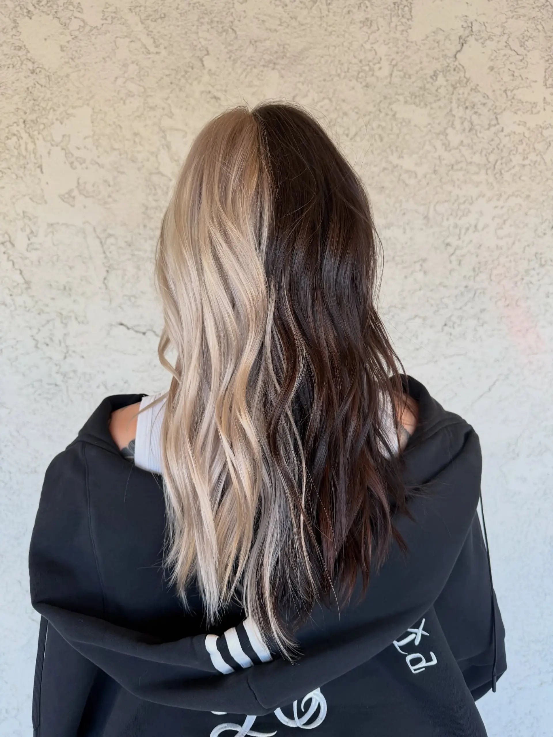 Long wavy hair styled in a high-contrast split dye, with one side light blonde and the other deep dark brown. 1