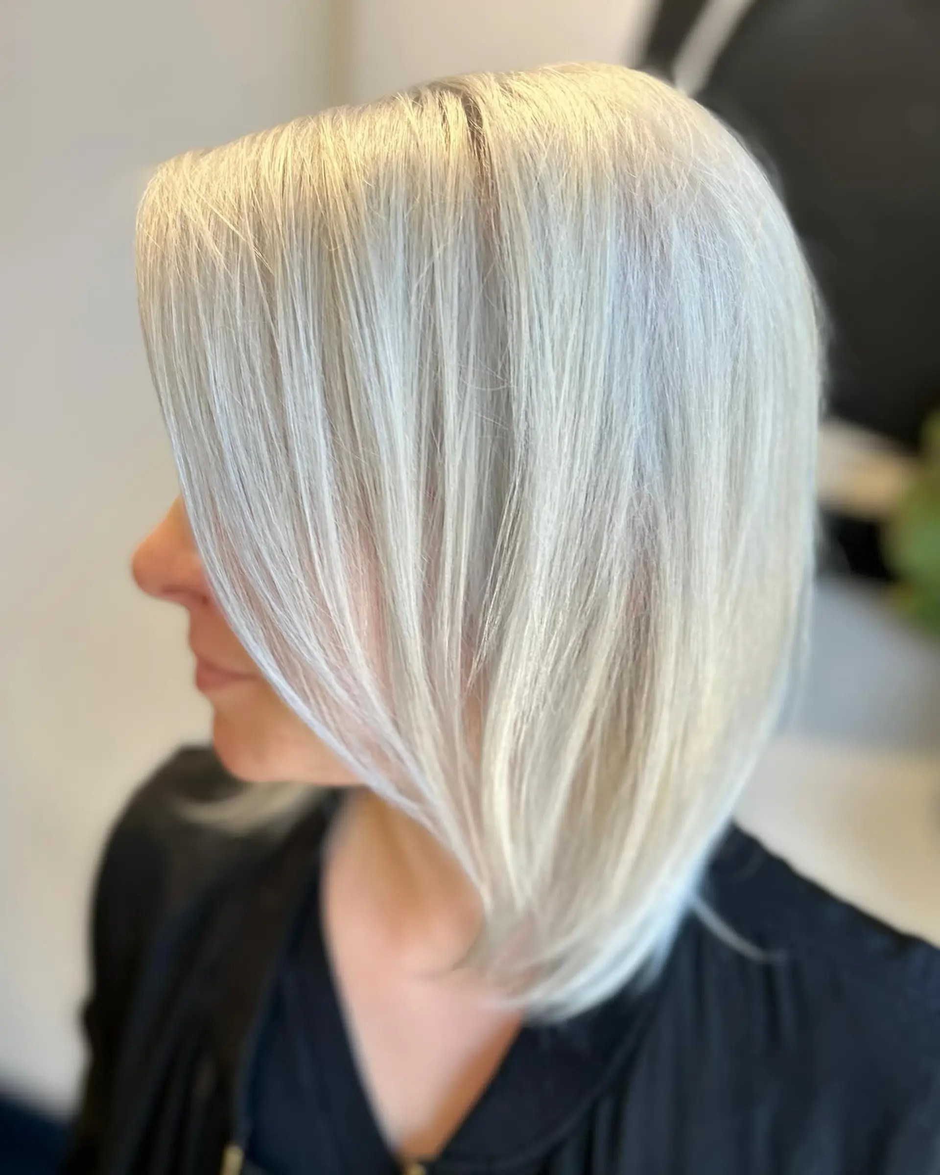 A sleek, bright white platinum blonde angled lob haircut with smooth texture and face-framing pieces. 1