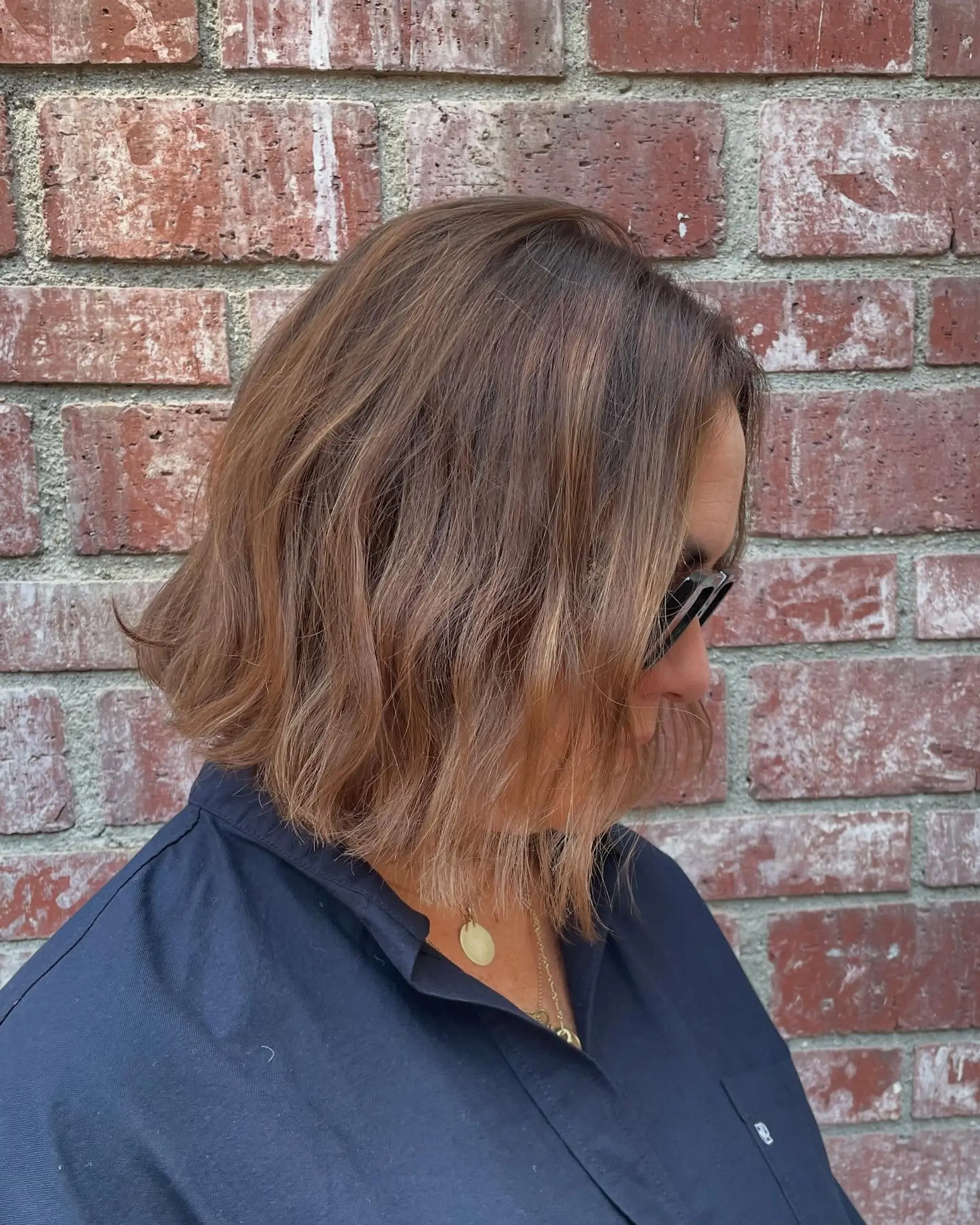 A textured short bob featuring soft, loose waves and subtle dimensional honey highlights over a brown base. 1