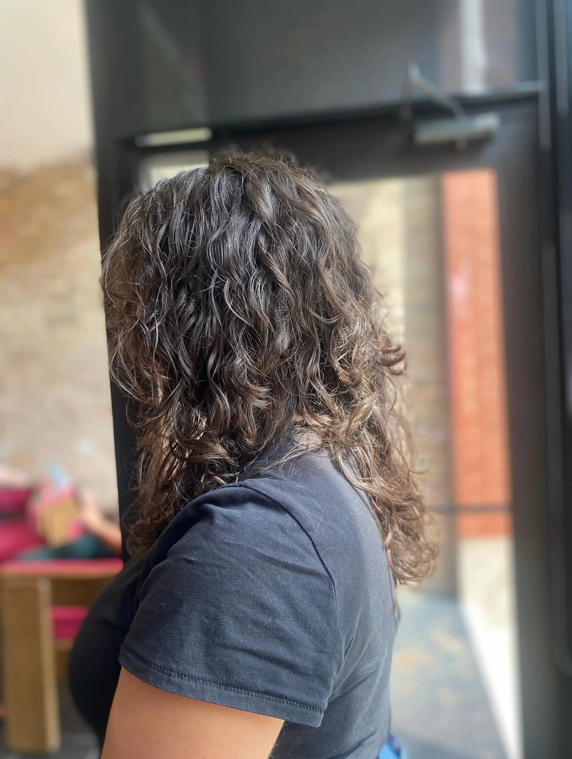 A medium-length curly hairstyle featuring a bronde balayage. 1