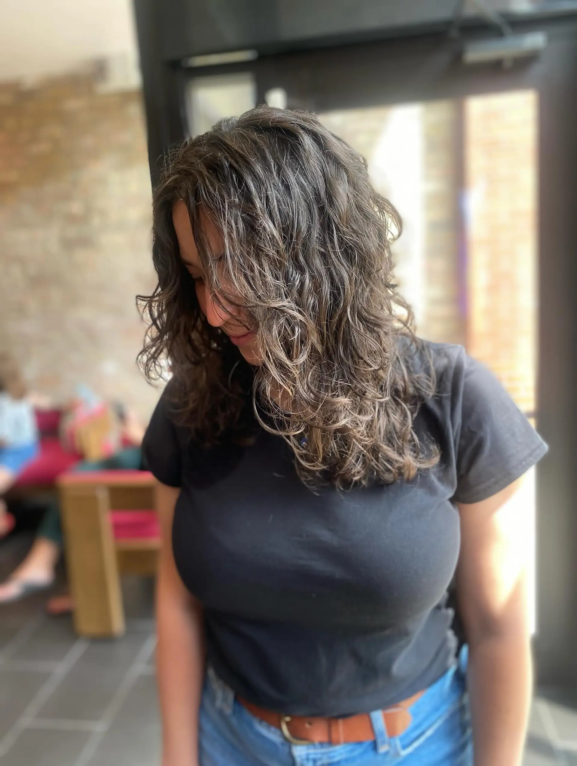 A medium-length curly hairstyle featuring a bronde balayage. 2
